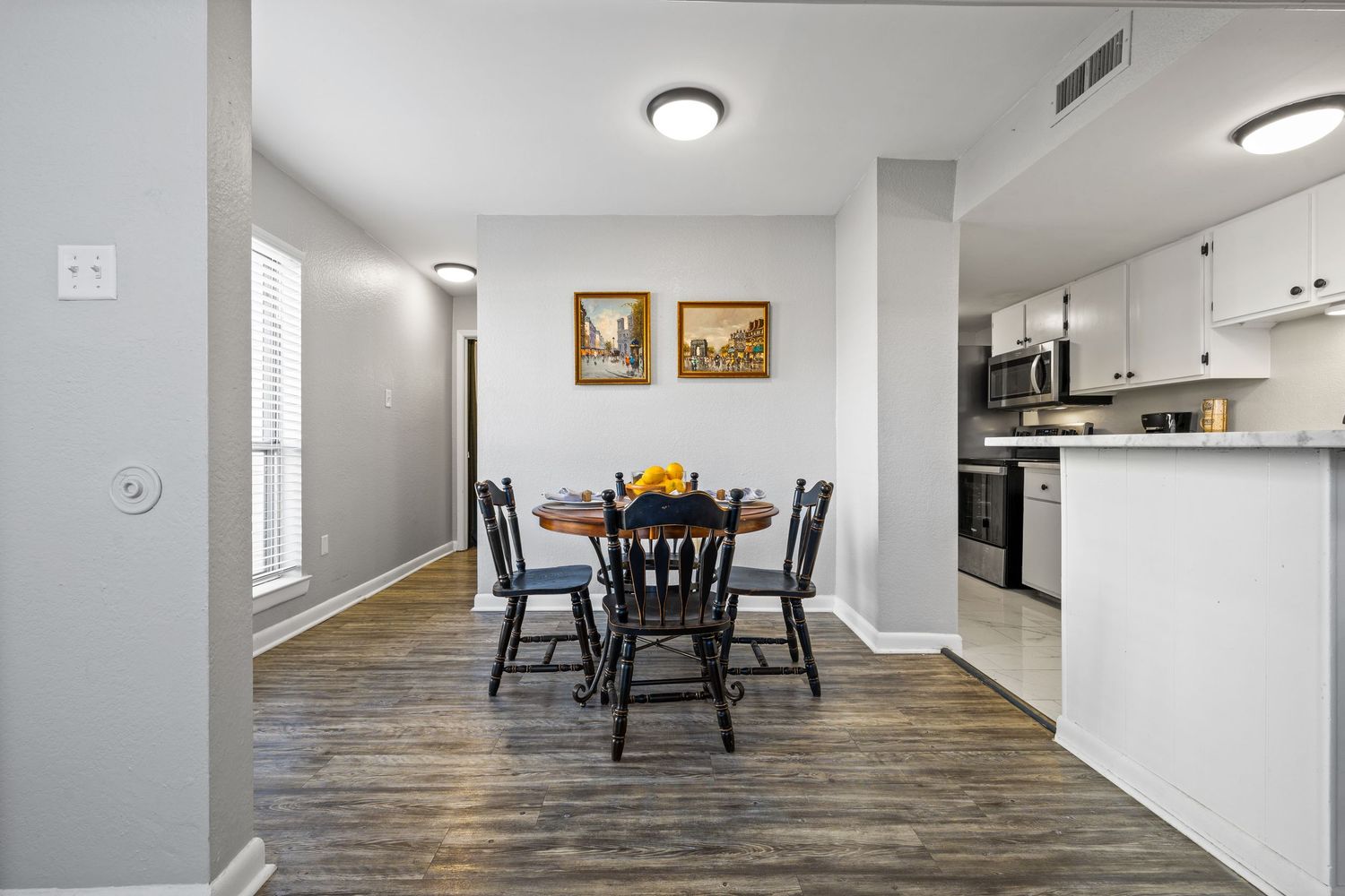 Empty residential room interior with rustic vinyl flooring, white walls, and recessed lighting.