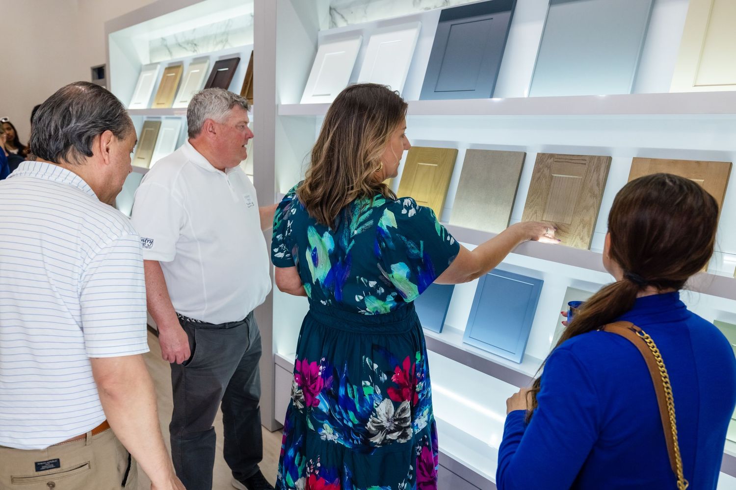 People browsing wall-mounted sample displays in a modern showroom, with a woman pointing at material swatches.