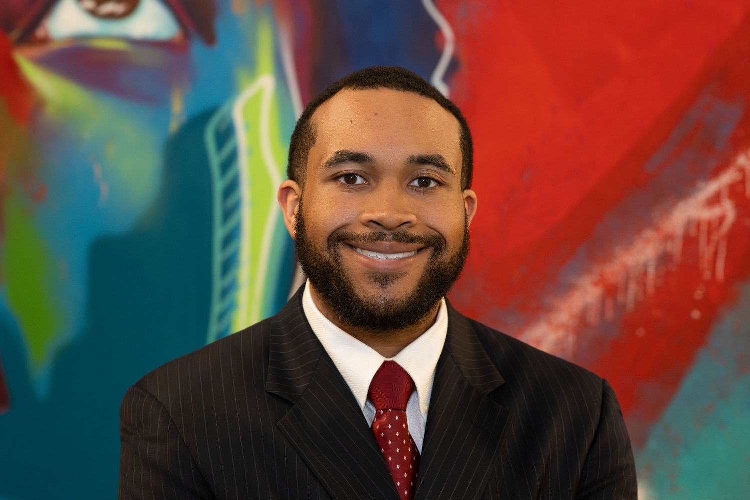 Professional headshots of business executives in formal attire against colorful backgrounds.