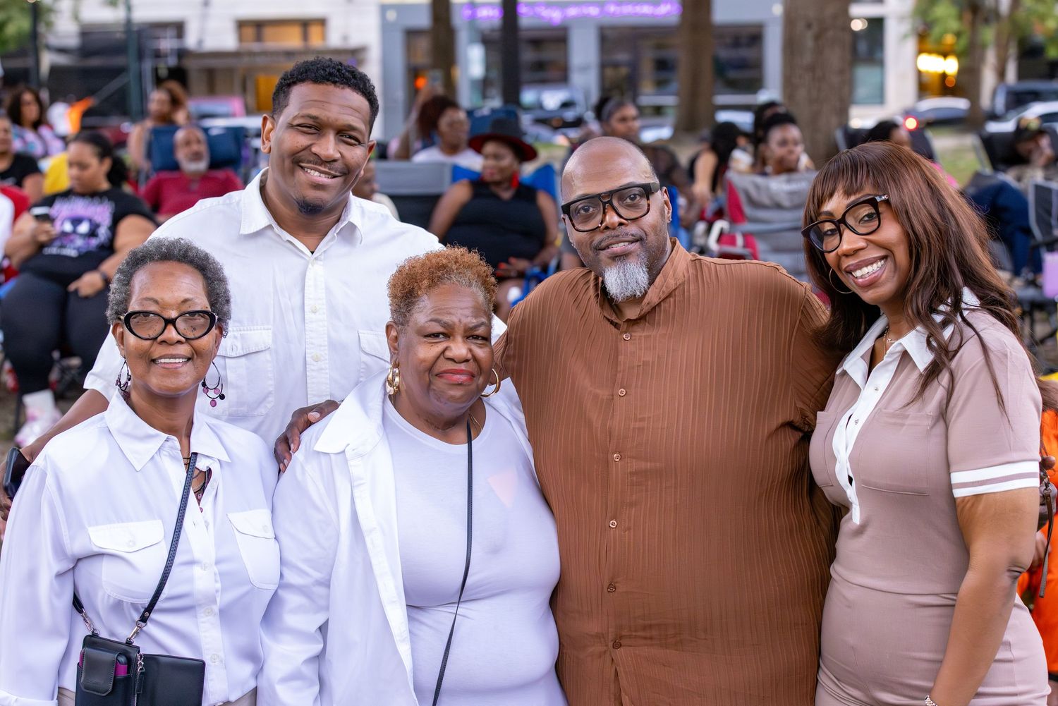 Group of people wearing white shirts at an outdoor community celebration.