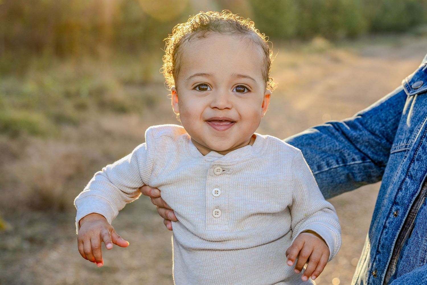 Baby wearing white sweater during golden hour outdoor photo session.