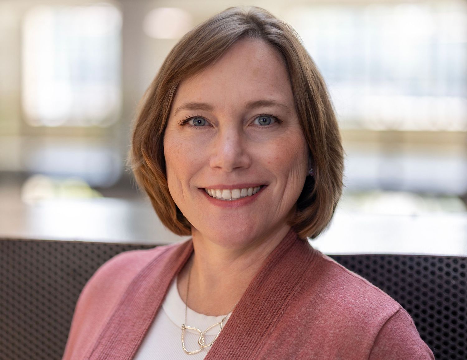 Professional portraits with warm expressions in a bright office setting.