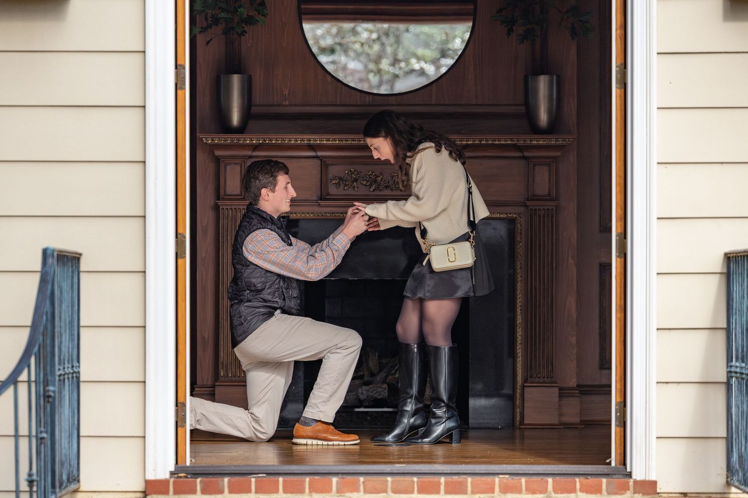 A romantic proposal moment captured in a doorway entrance with brick steps and a decorative wooden door.