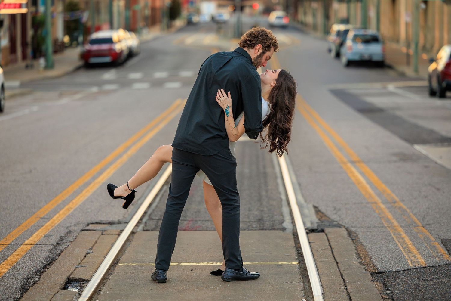 A couple dips and embraces in a romantic dance pose on an urban street with yellow lines.