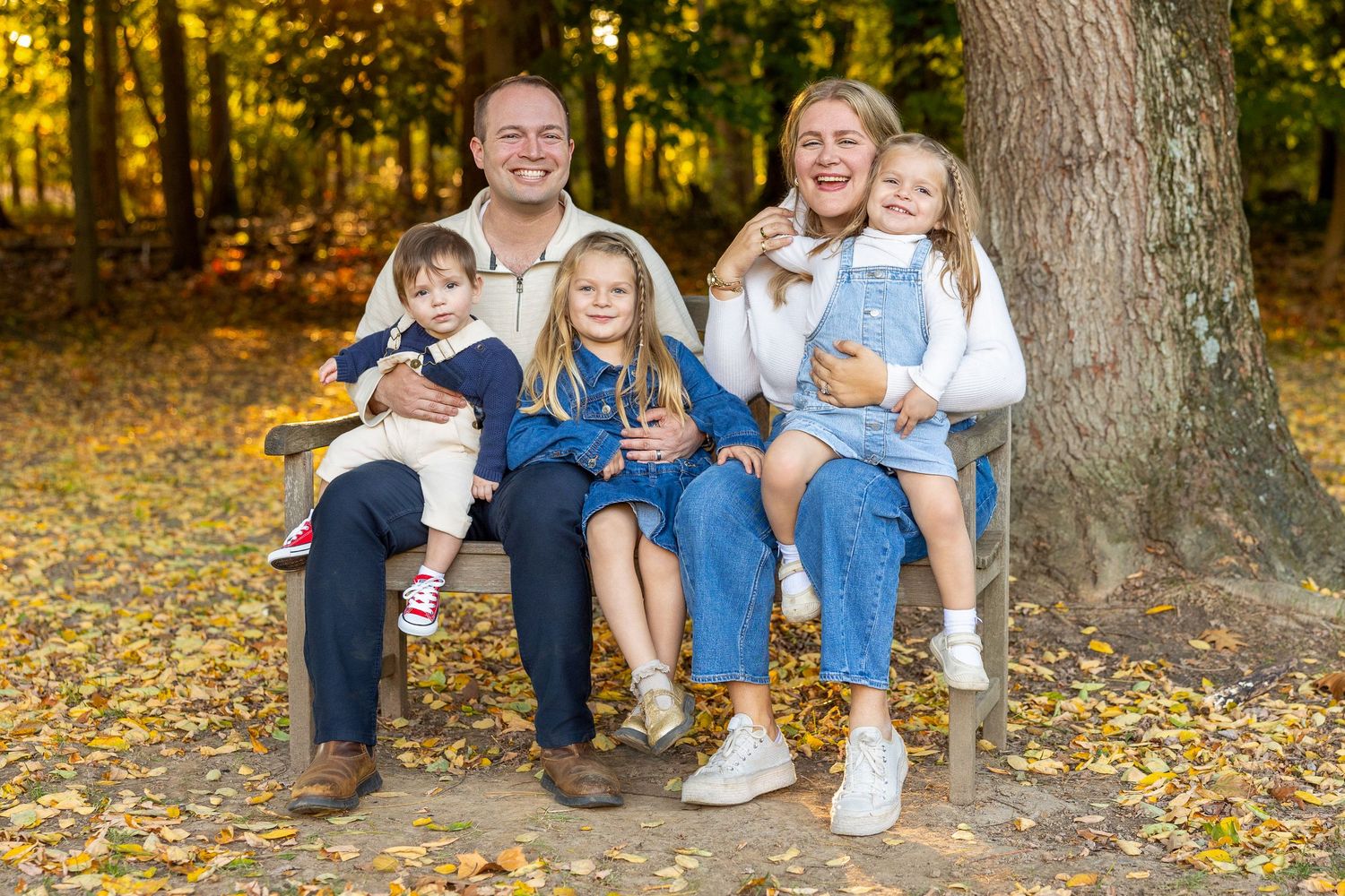 Family photo session in autumn forest with fallen leaves.