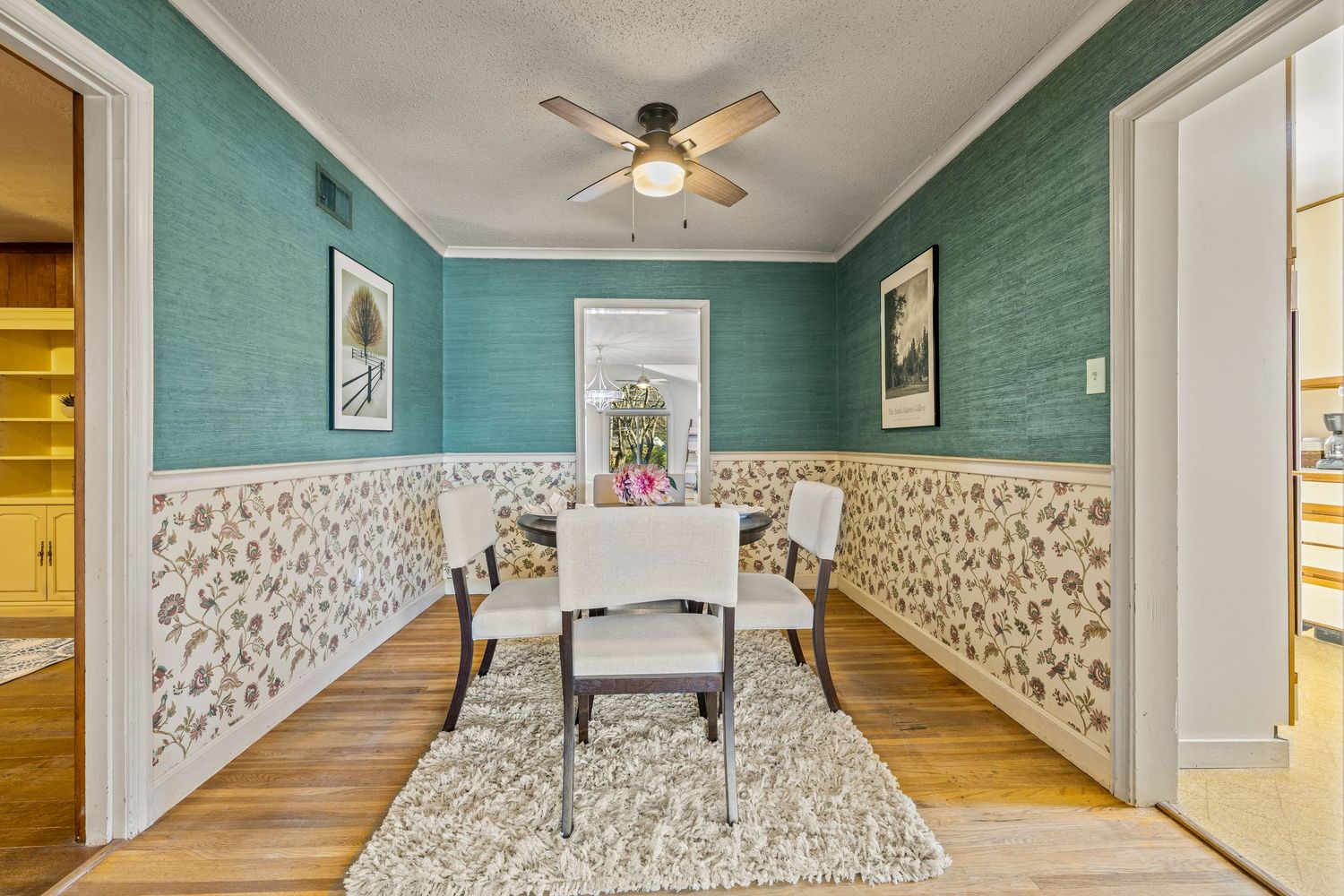 Panoramic view of a modern bedroom with turquoise walls, white wainscoting, and a ceiling fan.