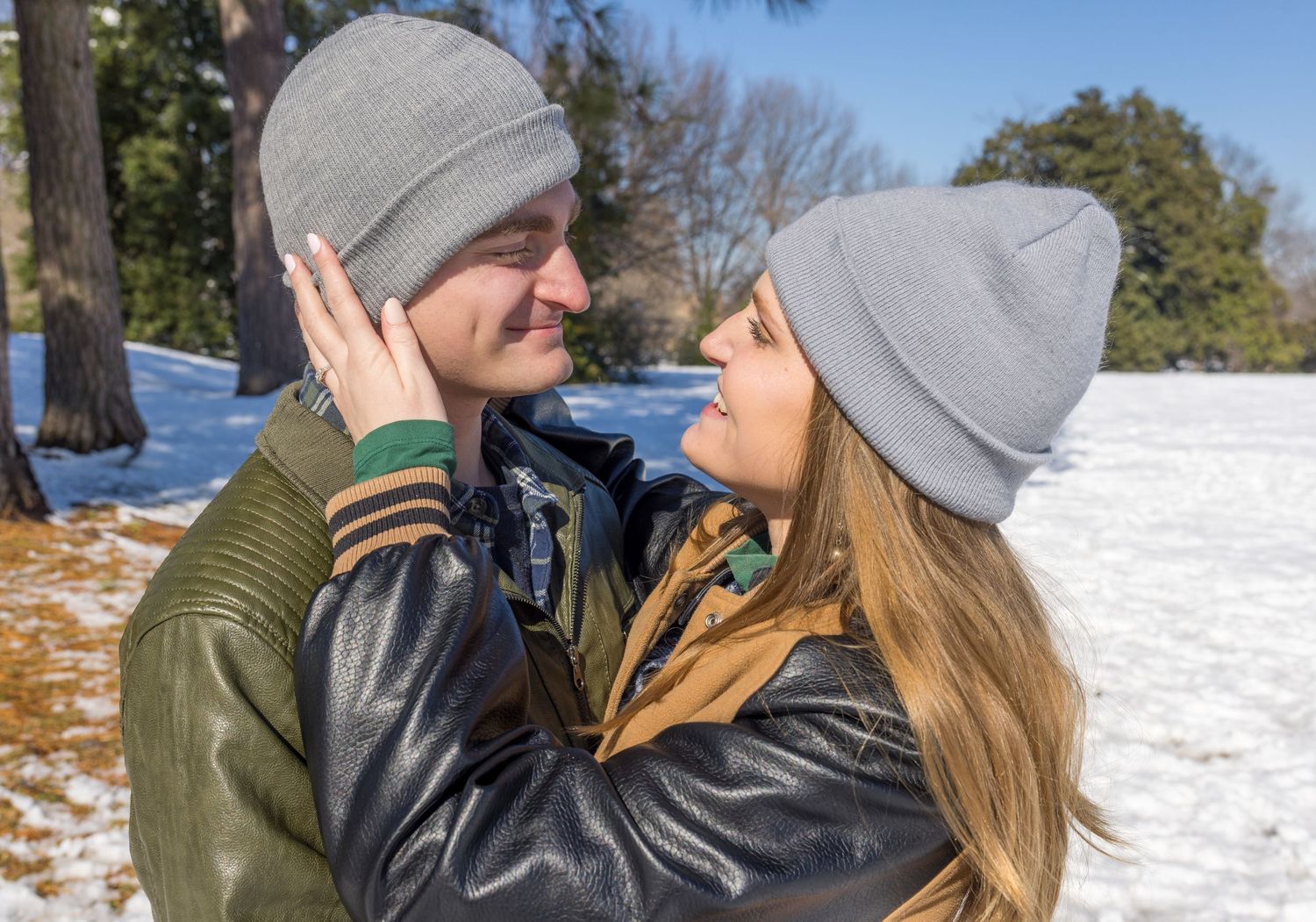 A couple in winter attire sharing an intimate moment in a snowy setting.