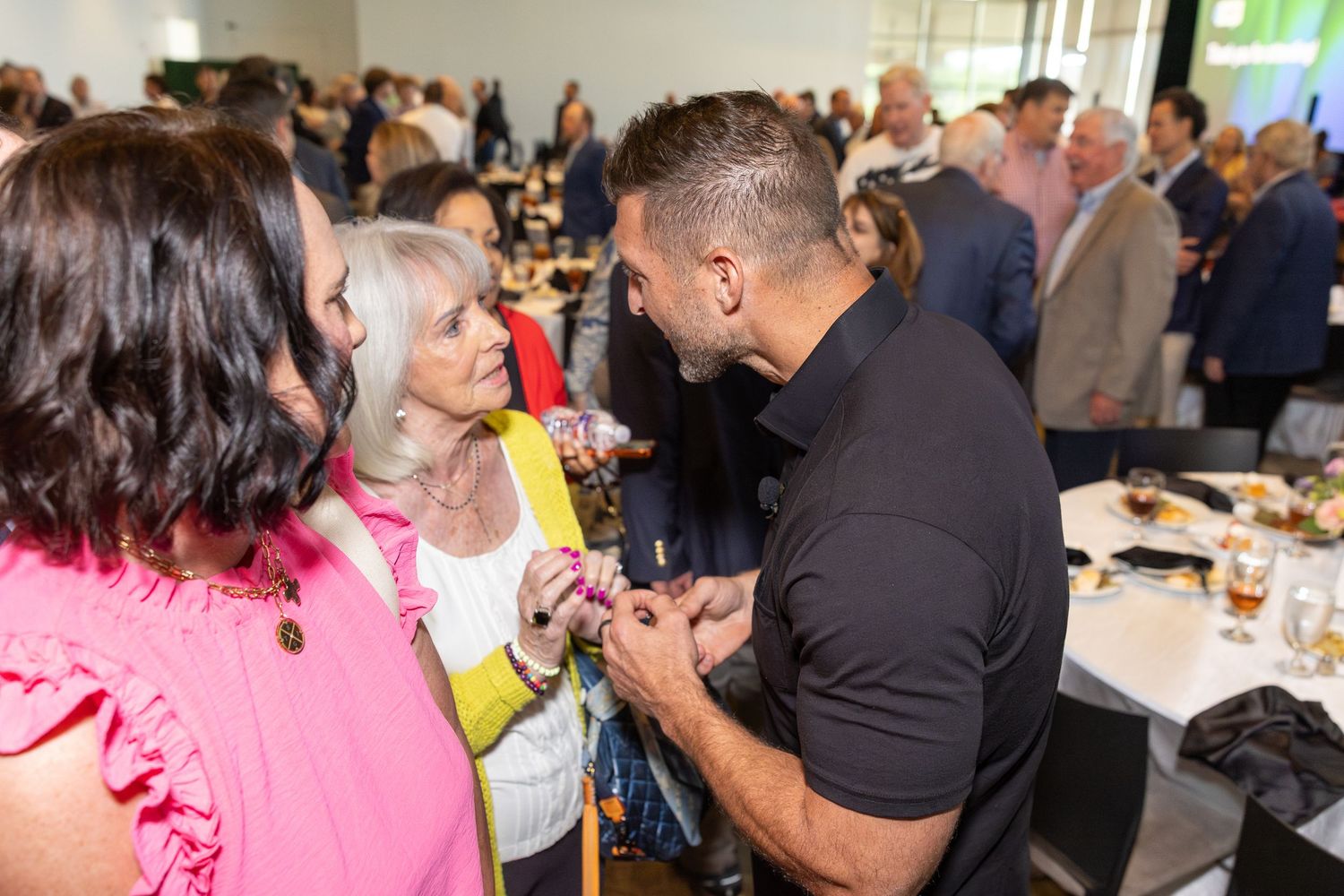 Guests networking and conversing at a busy indoor corporate event or business luncheon gathering.