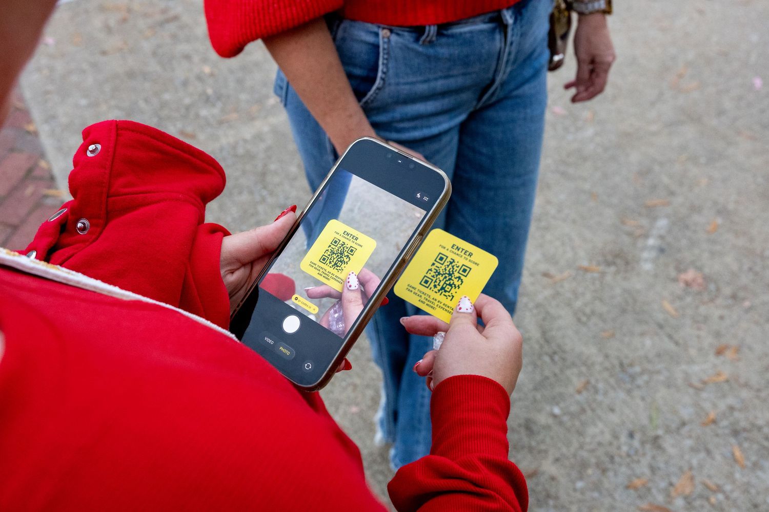 Person wearing red clothing holds electronic device outdoors.