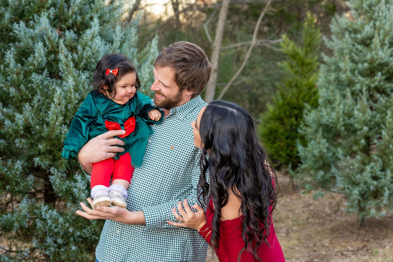Family shares joyful moments together during sunset photo session among evergreen trees.