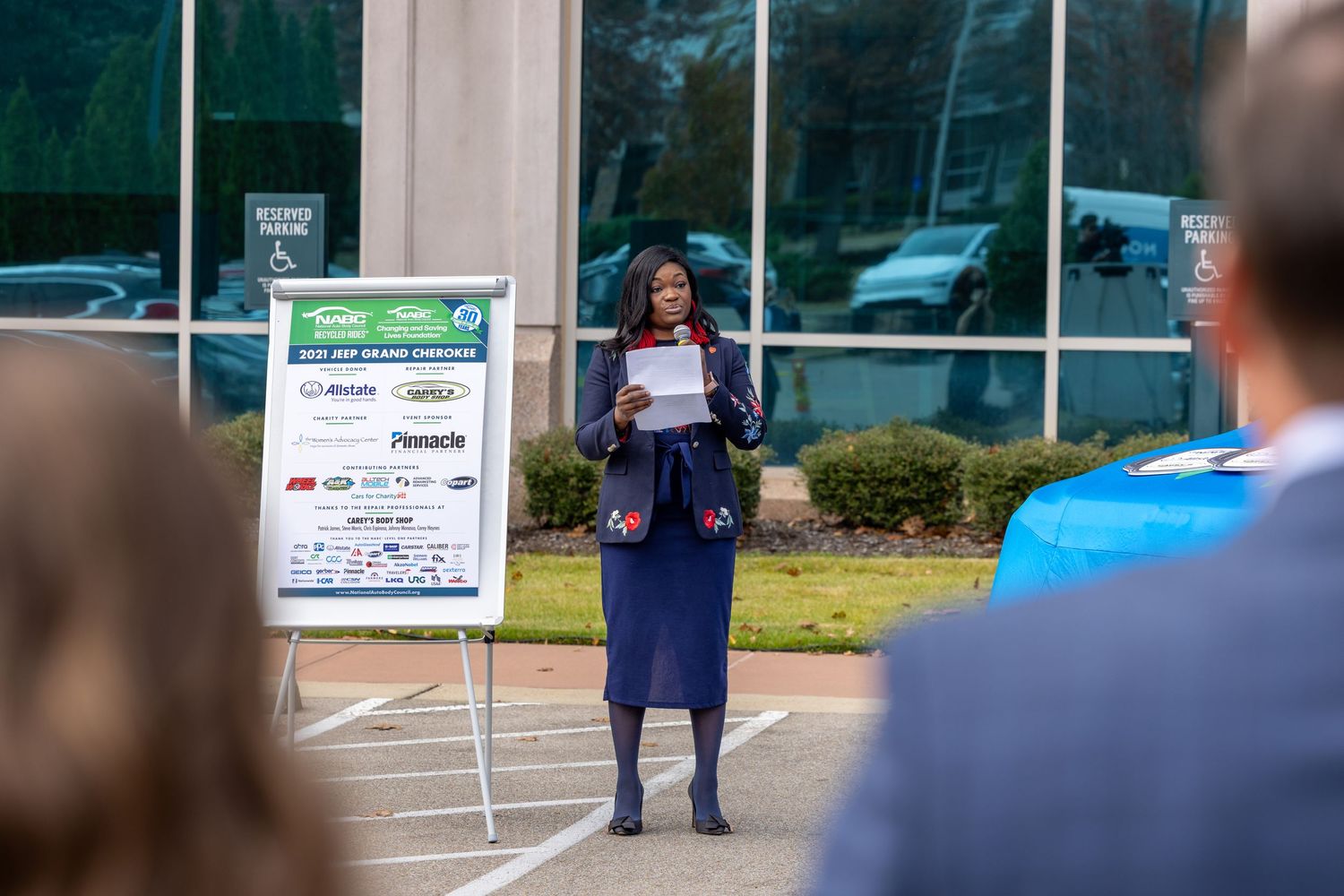 Corporate event setup with presentation boards and attendees gathered outside a building.