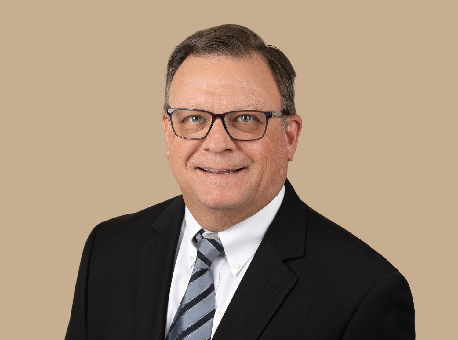 Business executive in glasses and suit against beige studio background.