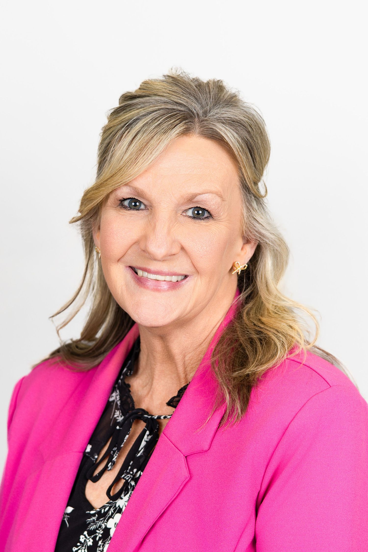 Business portrait of someone in hot pink blazer and black necklace against white background.