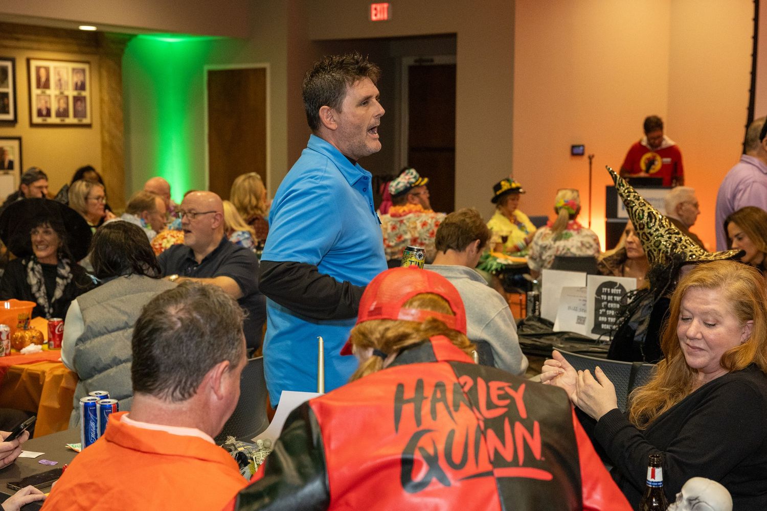 Large crowd gathered in an event hall with green and orange ambient lighting.