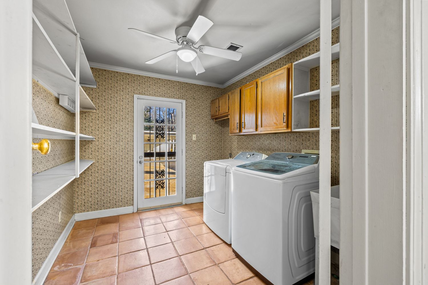 Spacious laundry room with white appliances, terracotta tile flooring, and wooden cabinets in a modern home.
