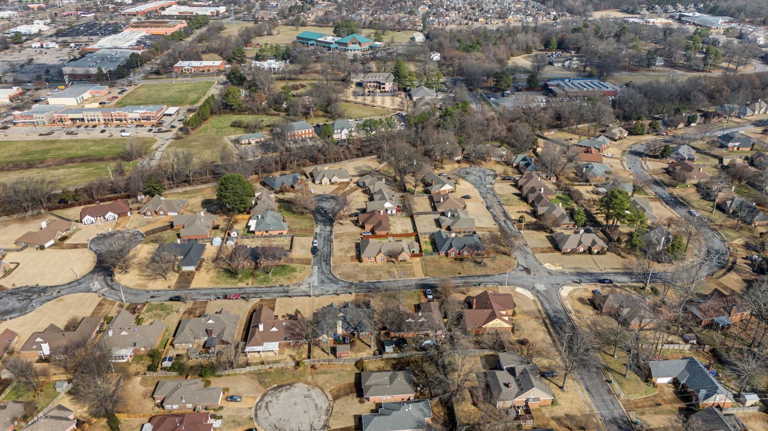 Aerial view of a large industrial facility with multiple buildings and storage tanks surrounded by suburban development.