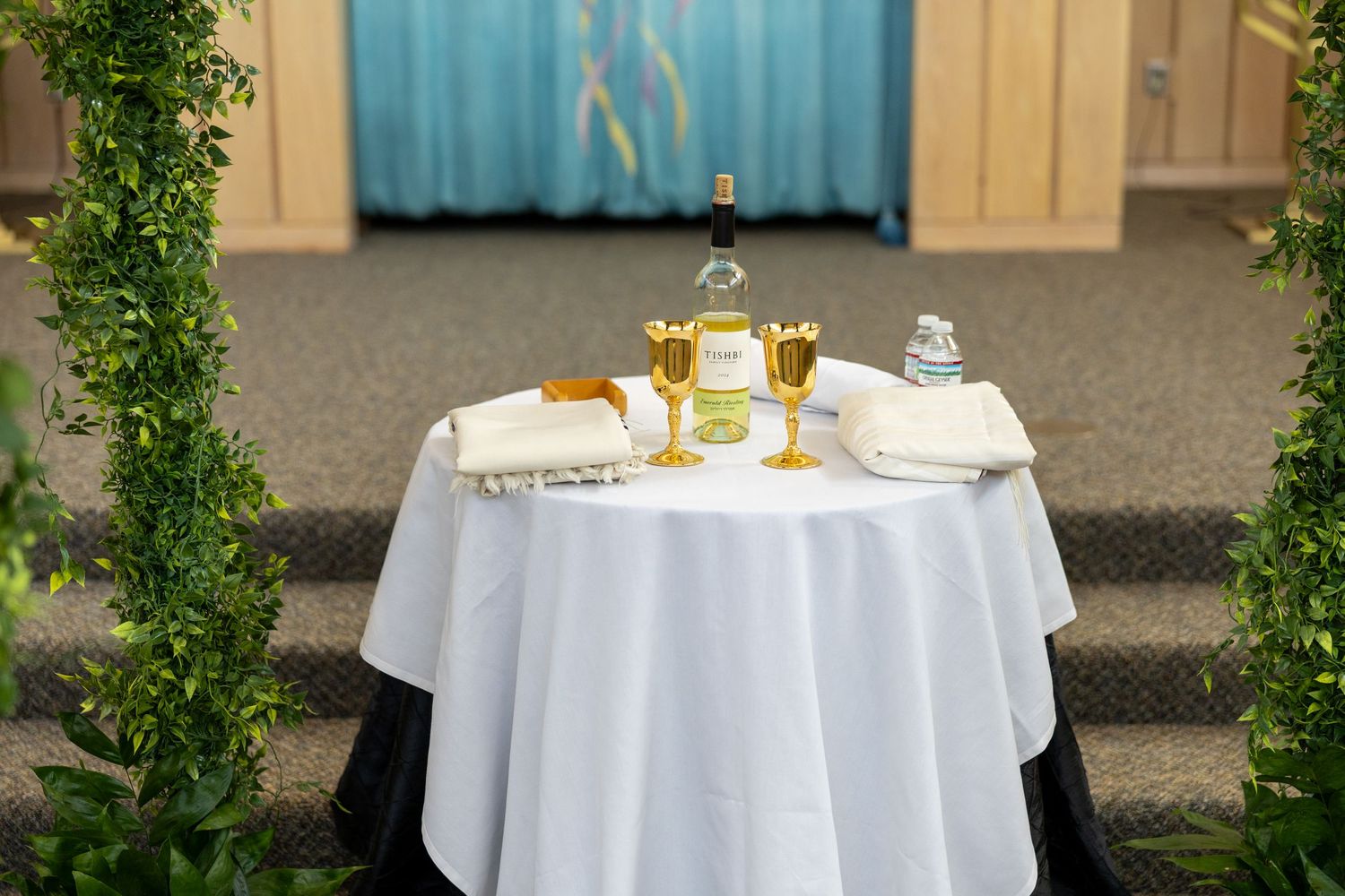 Elegant round tables with white tablecloths and place settings arranged outdoors for an upscale dining event.