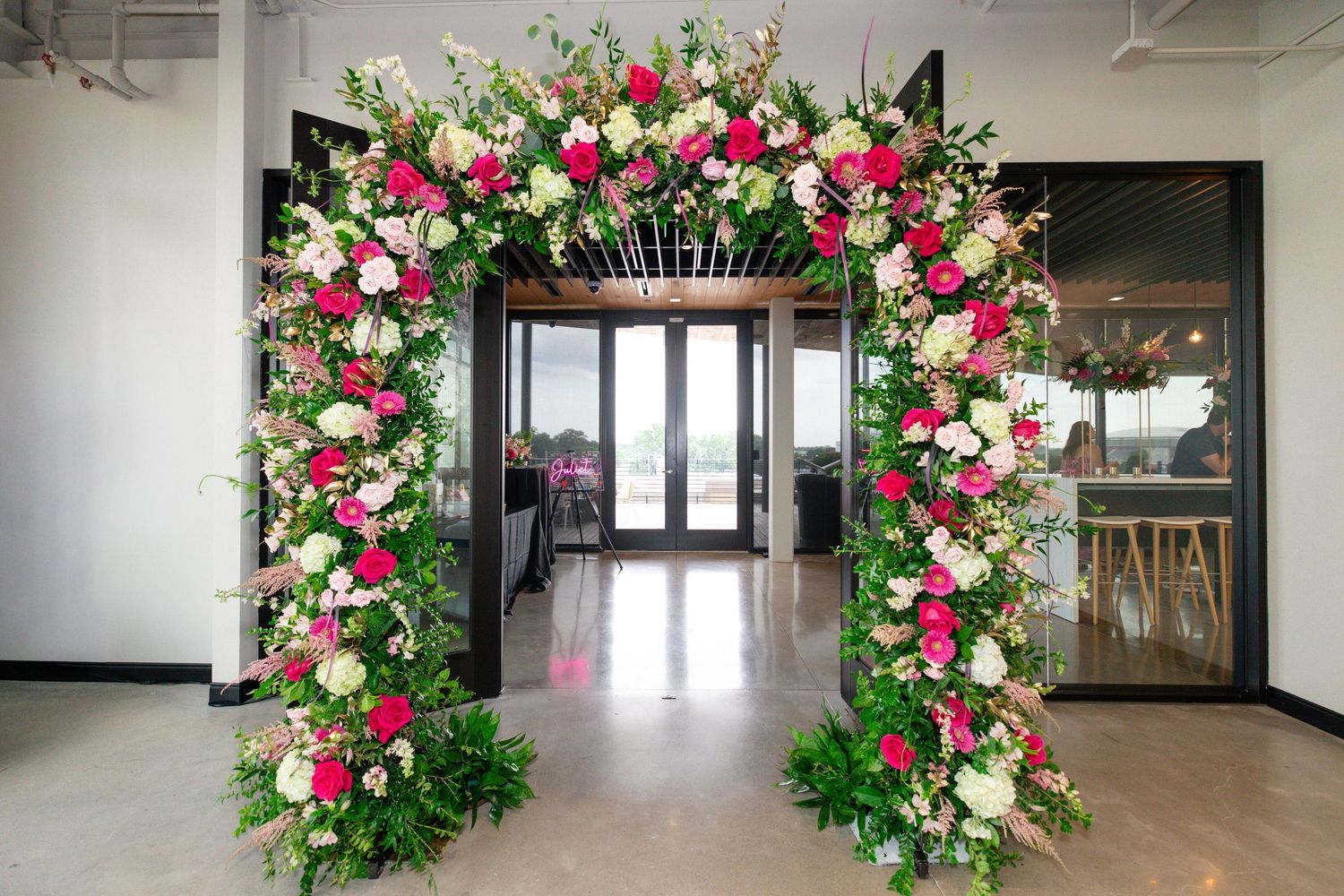 Elegant floral arch with pink and white roses framing a doorway at a wedding venue.