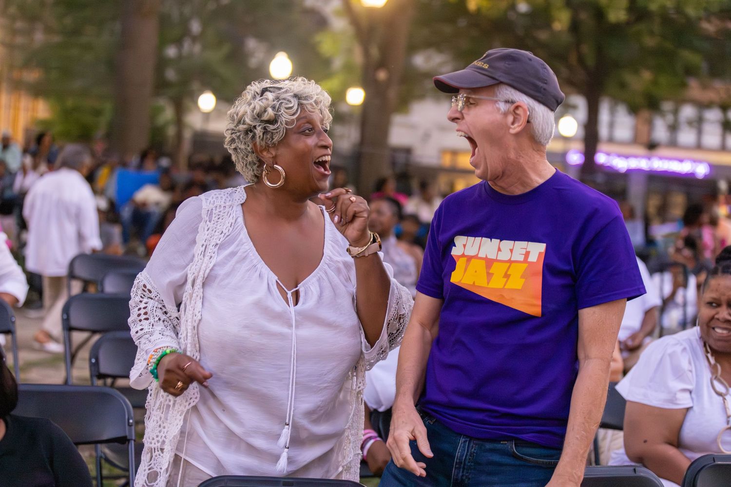 A group celebrates outdoors during sunset with joyful expressions and laughter.