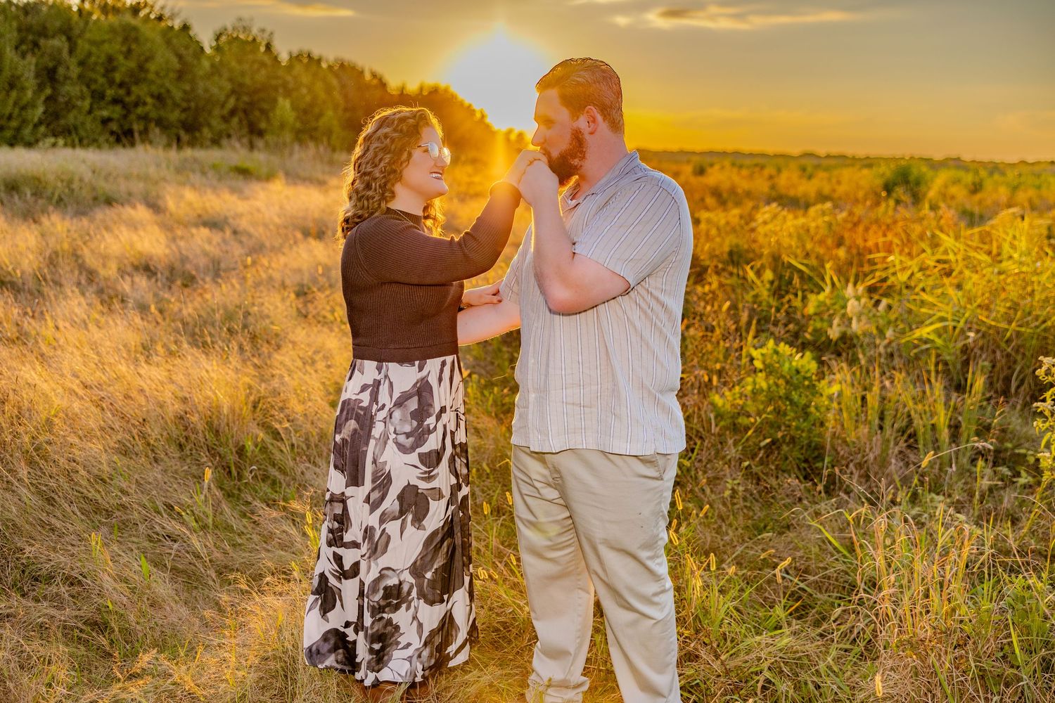 Romantic dance poses captured against glowing sunset in grassy field.