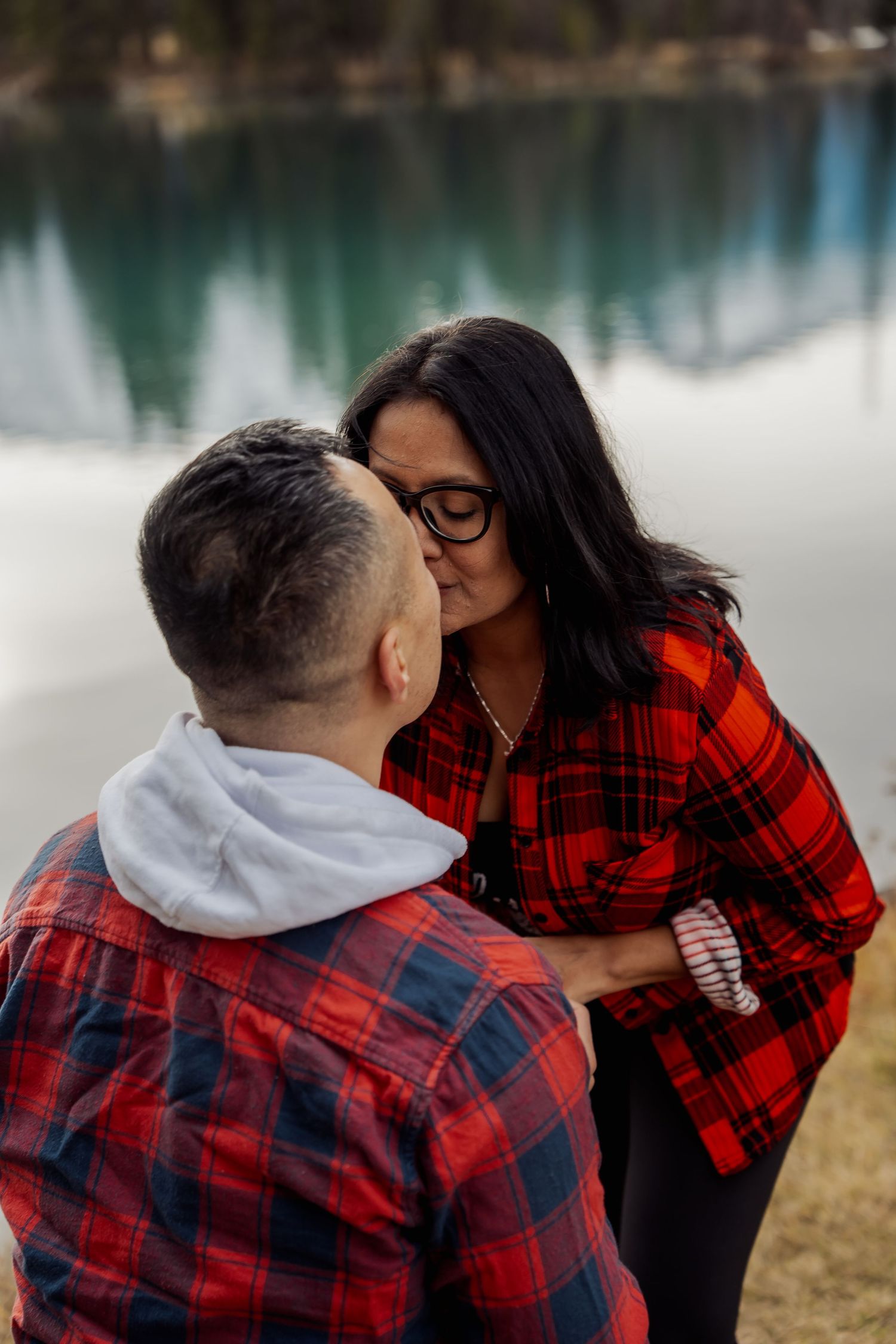 A romantic lakeside moment between a couple wearing coordinating outfits.