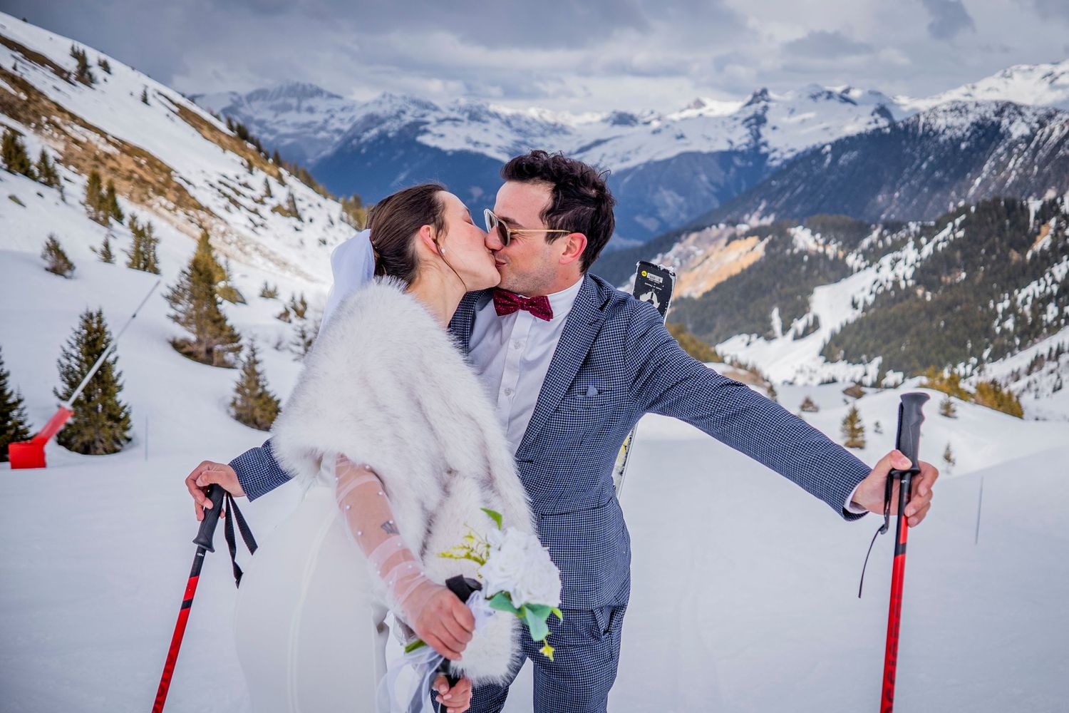 Romantic winter wedding photos on ski slopes with snow-capped mountains in the distance.