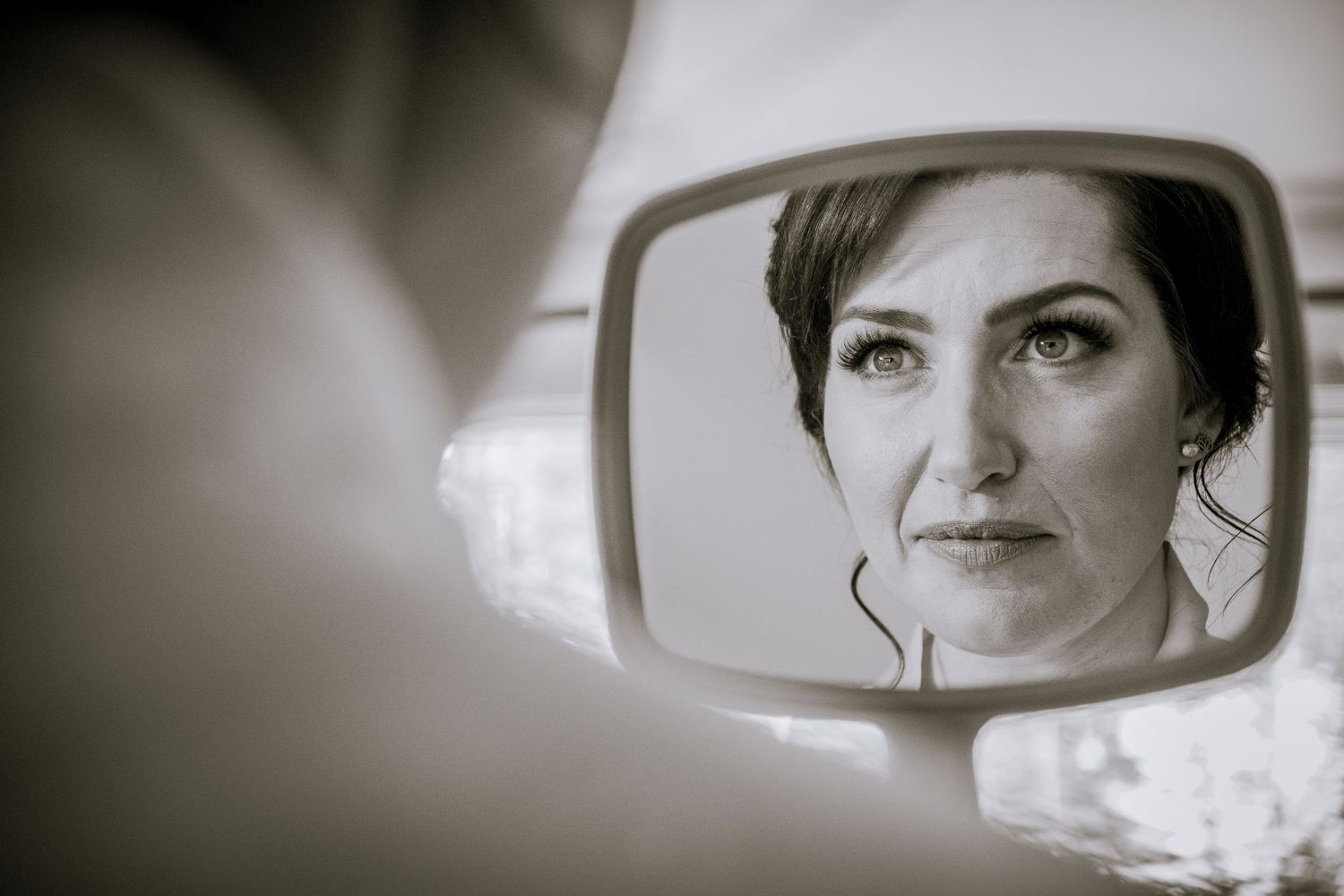 A black and white reflection in a car side mirror shows a contemplative expression.
