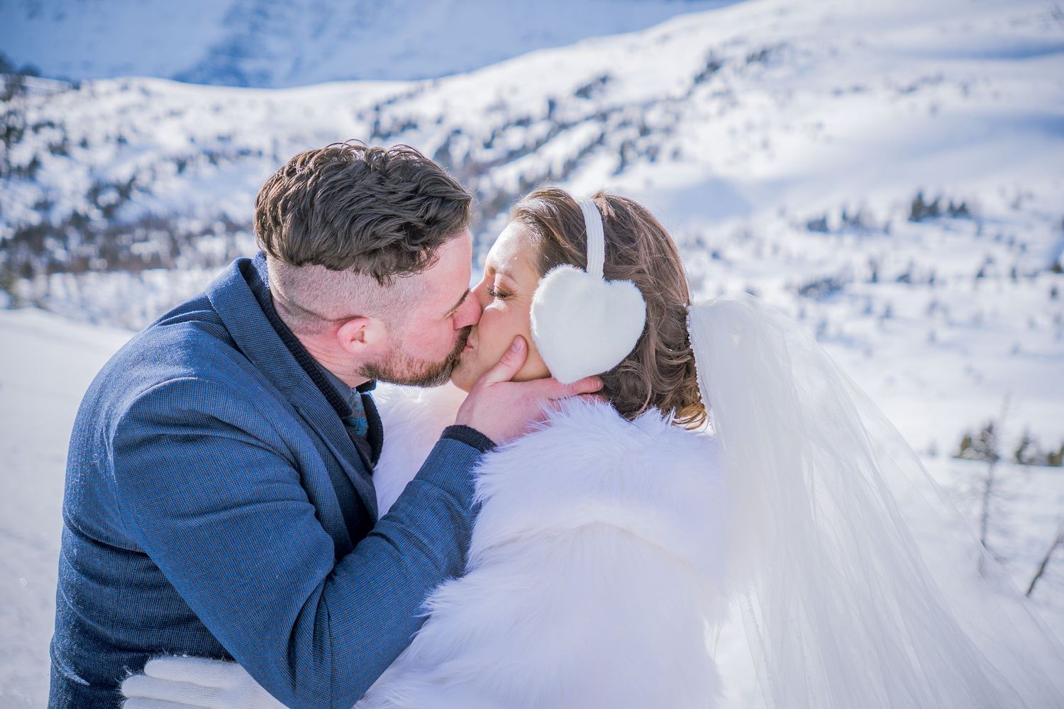 A romantic winter wedding photo shoot in snowy mountain landscape with couple embracing in scenic white surroundings.