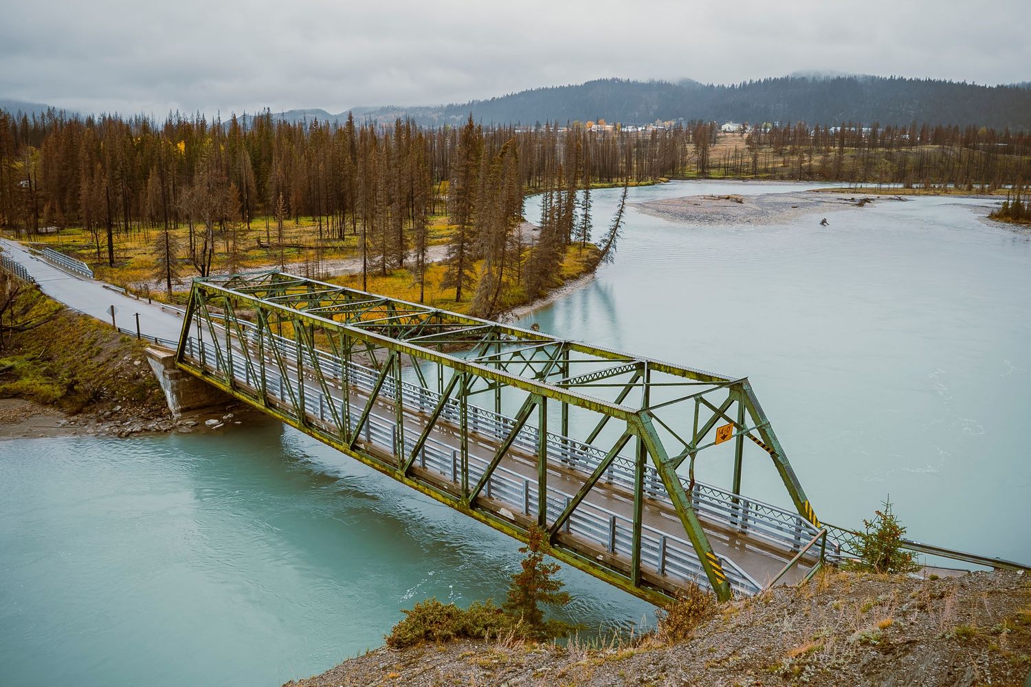 A series of panoramic shots showing a steel bridge spanning across a turquoise glacial lake in a mountainous landscape.