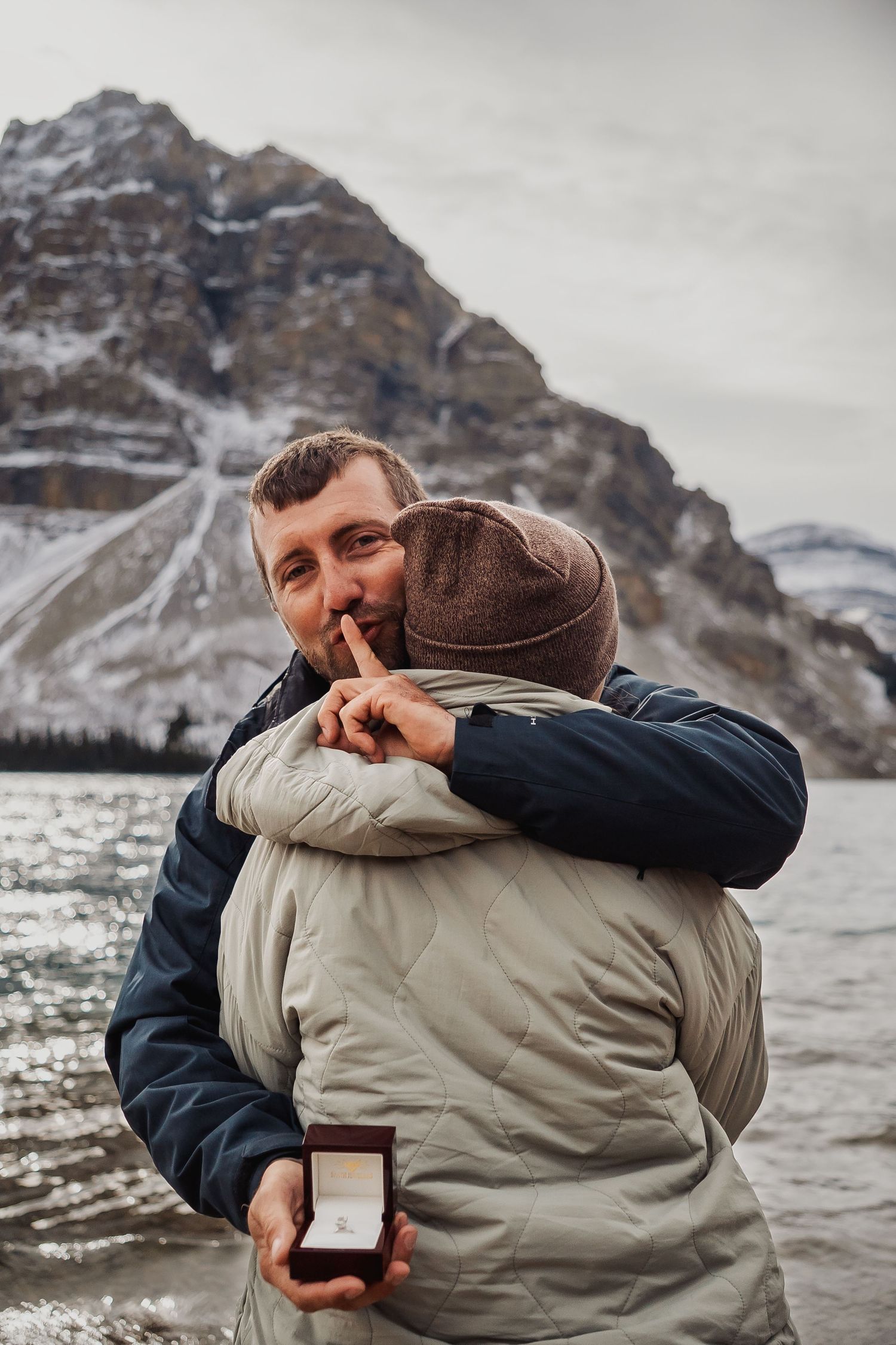 Intimate moment captured against snowy mountain backdrop in winter setting.