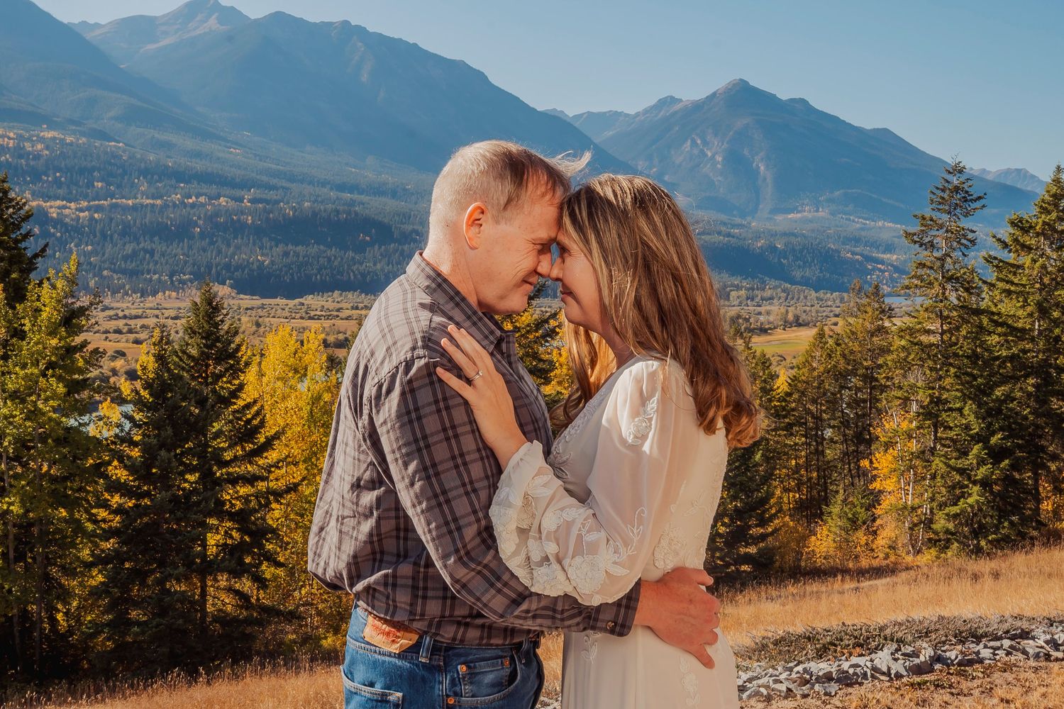 Romantic moment captured in mountain meadow with dramatic peaks in background.