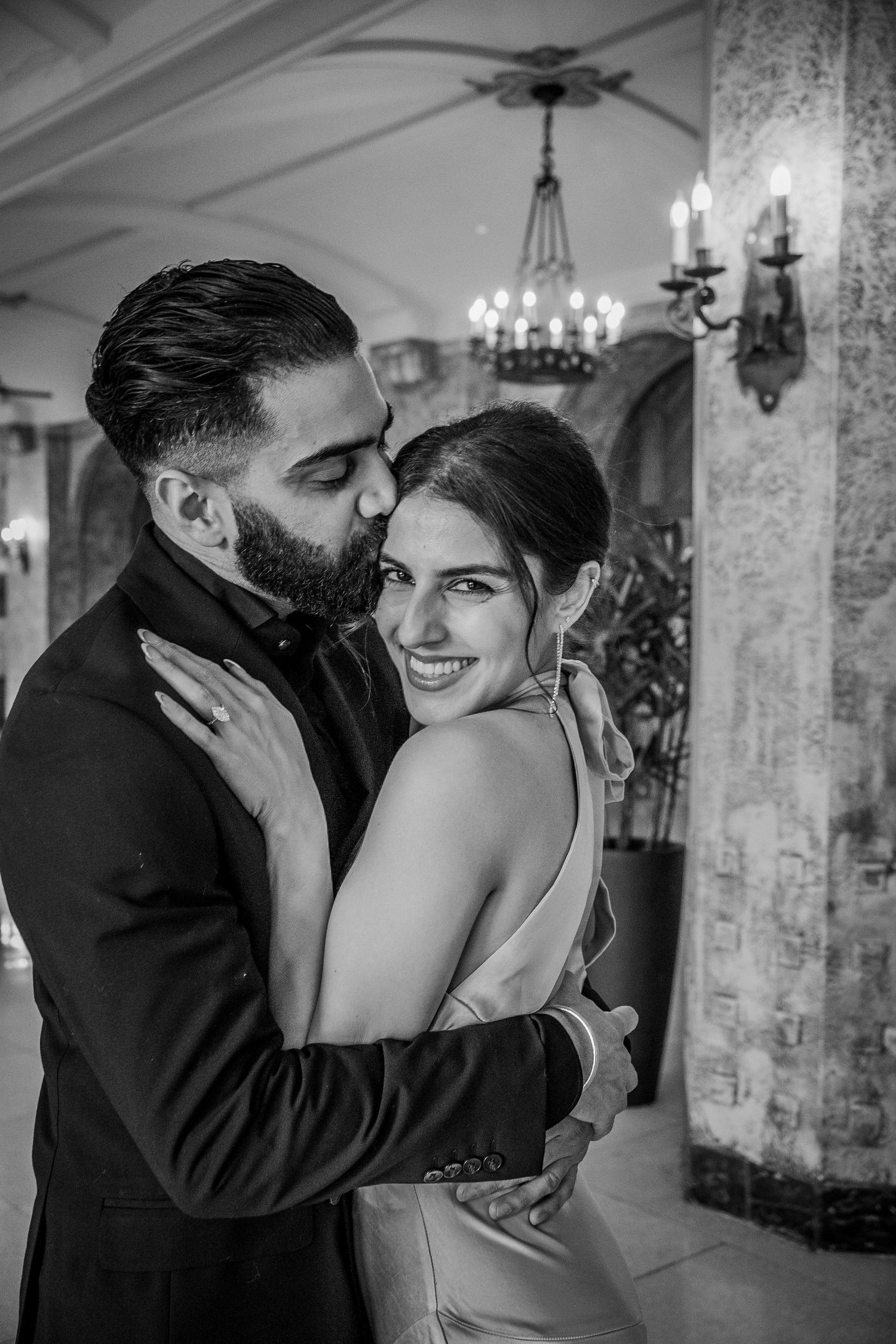 A romantic black and white sequence shows a tender moment between newlyweds sharing kisses in an elegant venue.