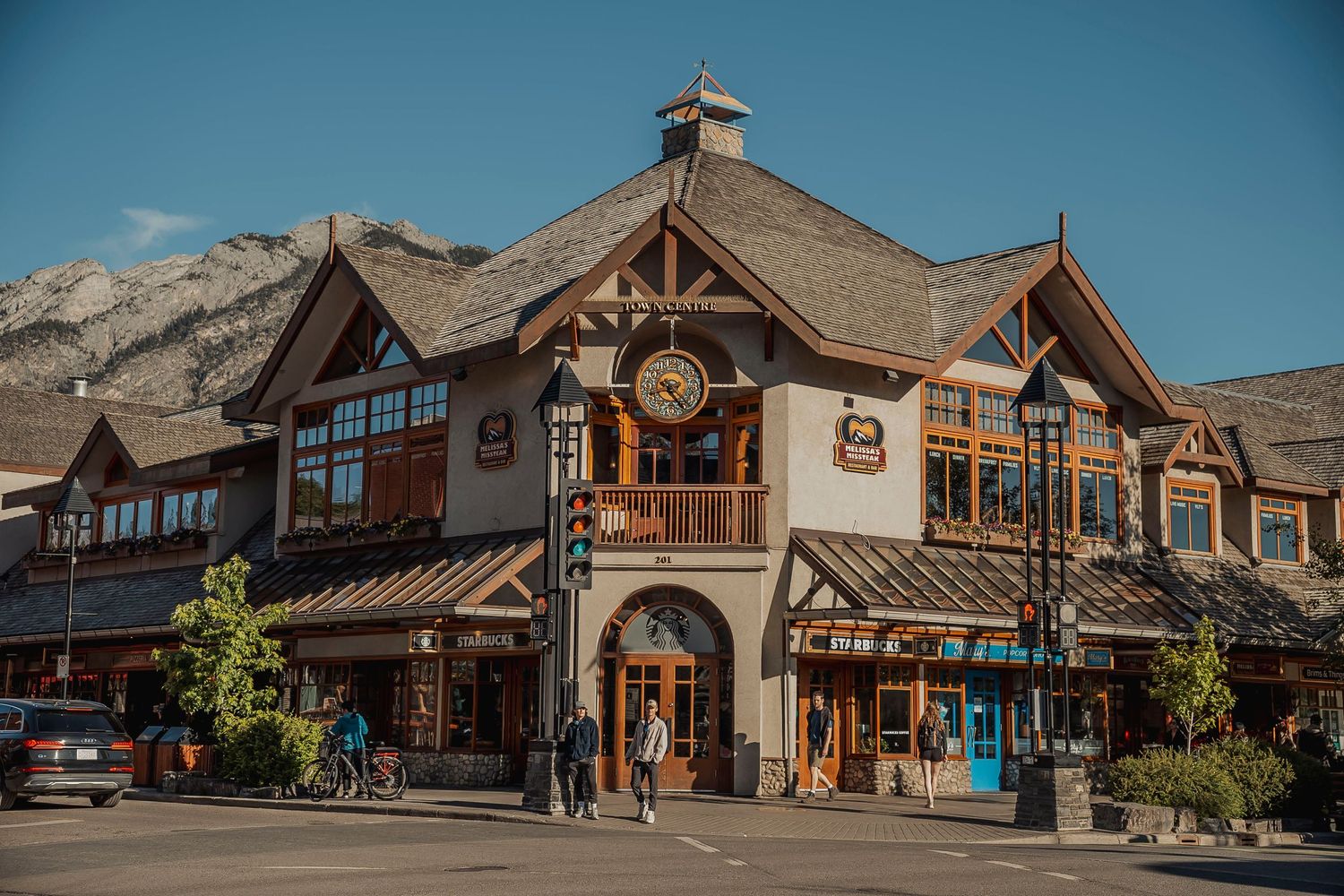 Rustic alpine-style shopping complex with wooden beams and stone accents in downtown Banff against mountain backdrop.