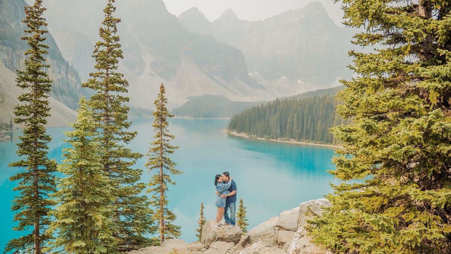 Stunning turquoise lake surrounded by snow-capped mountains and evergreen trees in a scenic mountain landscape.