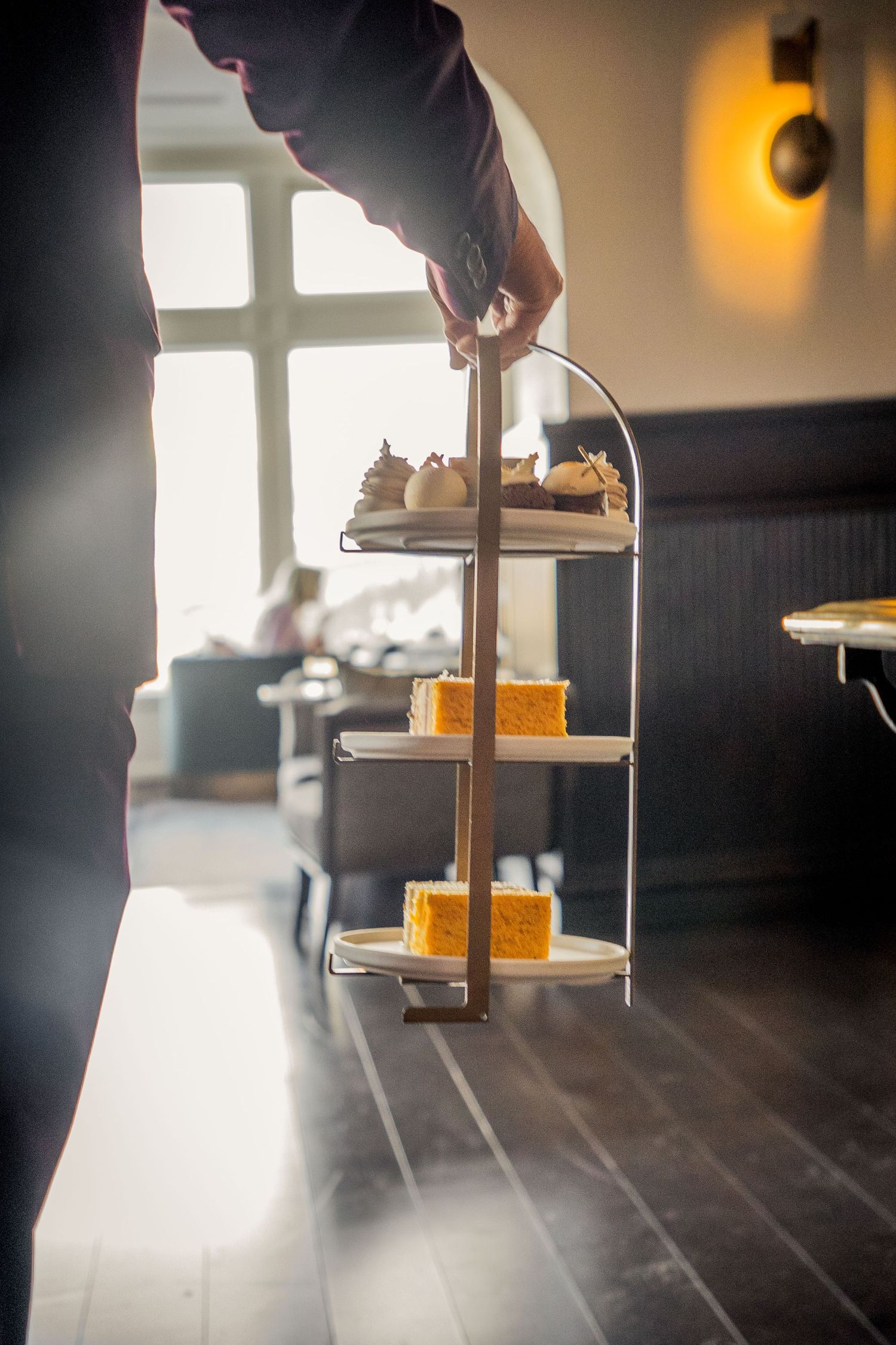 A series of low-angle shots showing a tiered serving tray with orange desserts in a dimly lit restaurant setting.