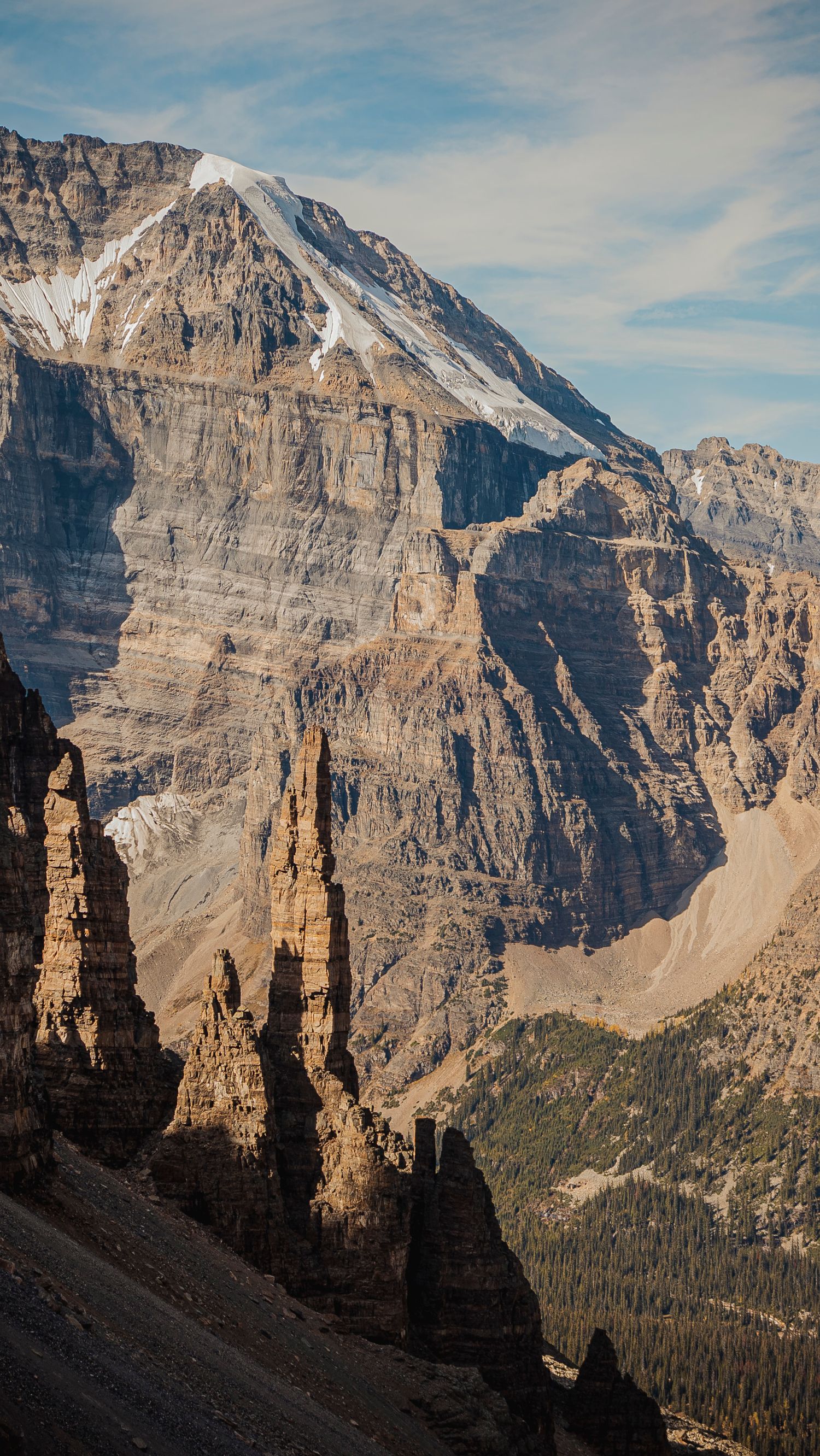 Majestic rocky spires and cliffs of the Canadian Rockies tower against a blue sky in Banff National Park.
