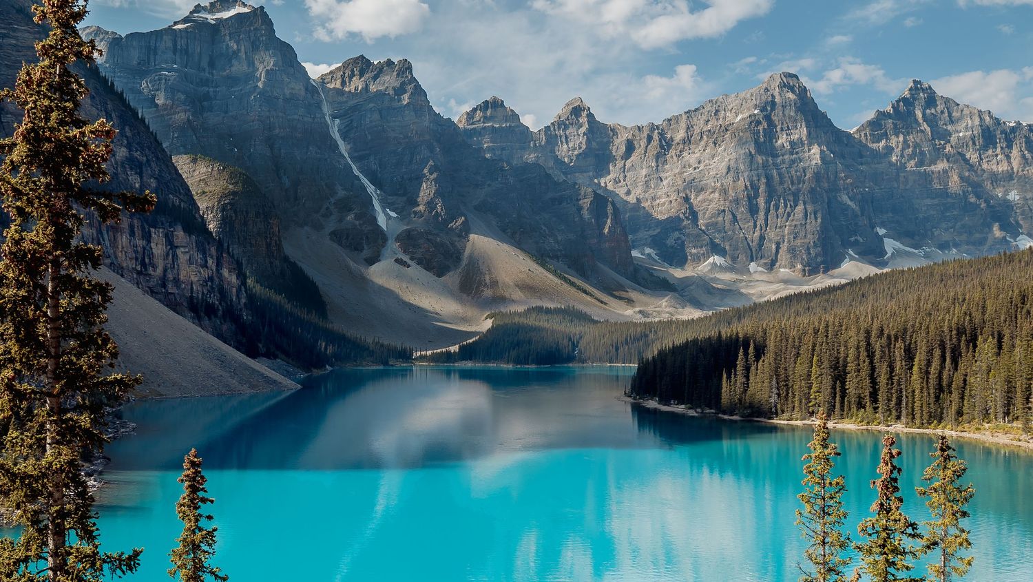Stunning turquoise waters of Moraine Lake reflect majestic snow-capped peaks in Banff National Park, Canada.