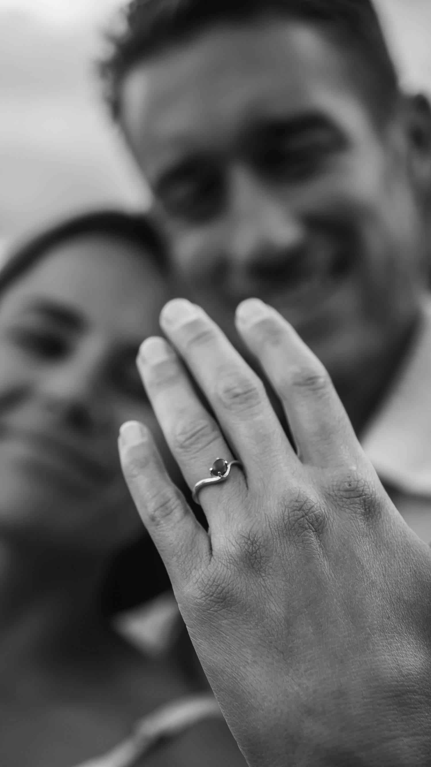 Close up black and white photo of hands wearing engagement rings.