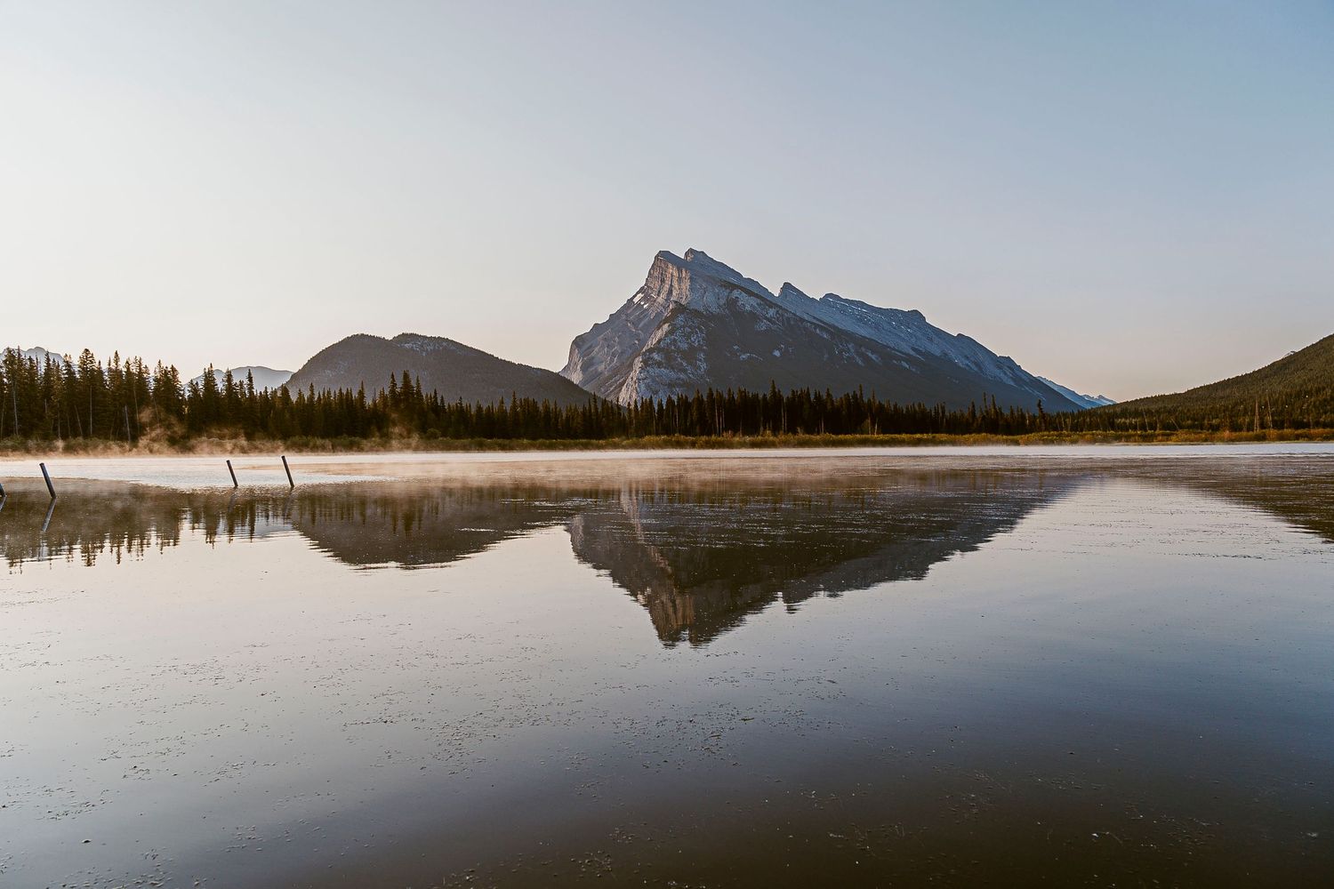 Panoramic view of a serene mountain lake at sunset with perfect reflections on still water.