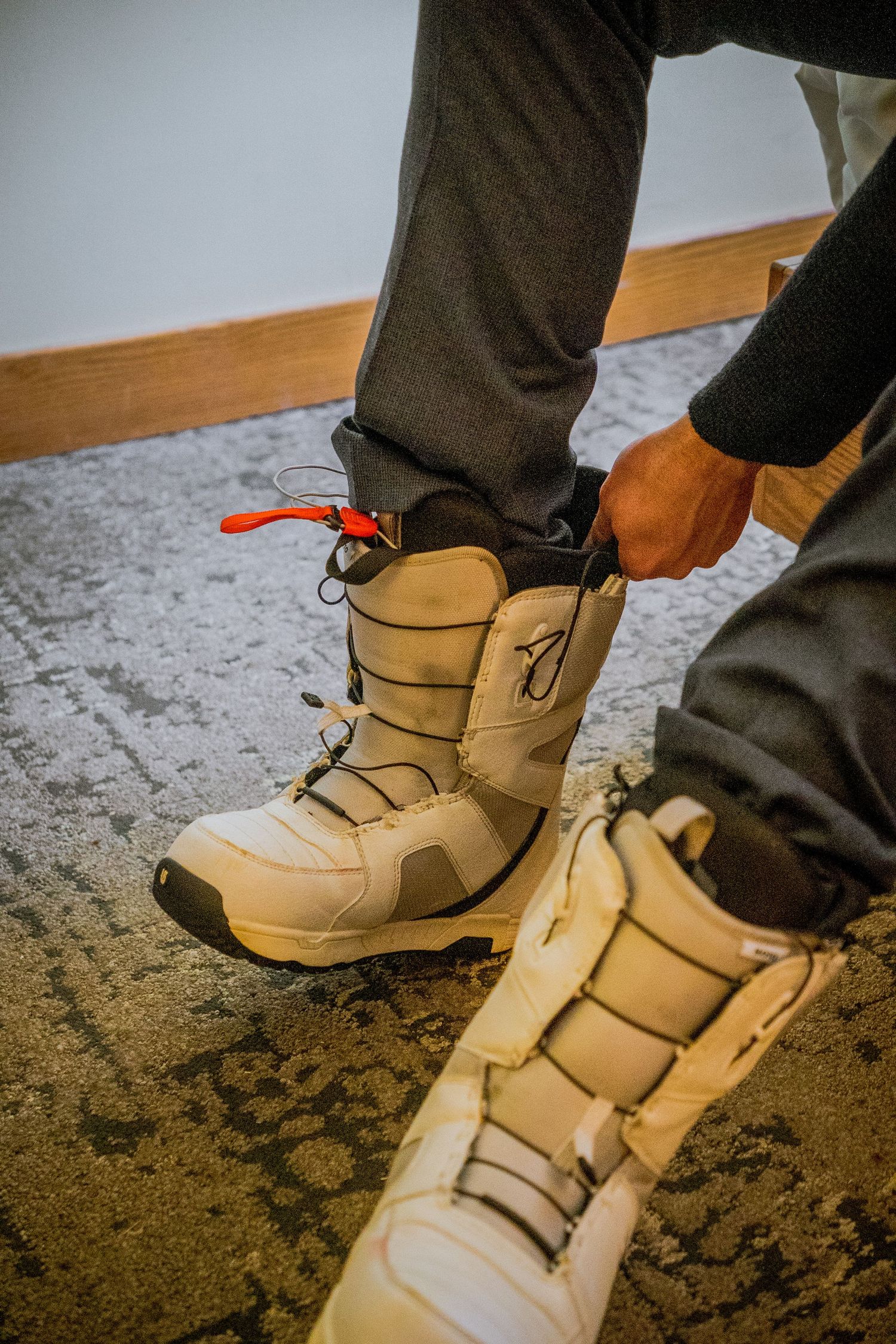 Sequence showing tan boots with velcro straps being fastened one by one against a dark carpet background.
