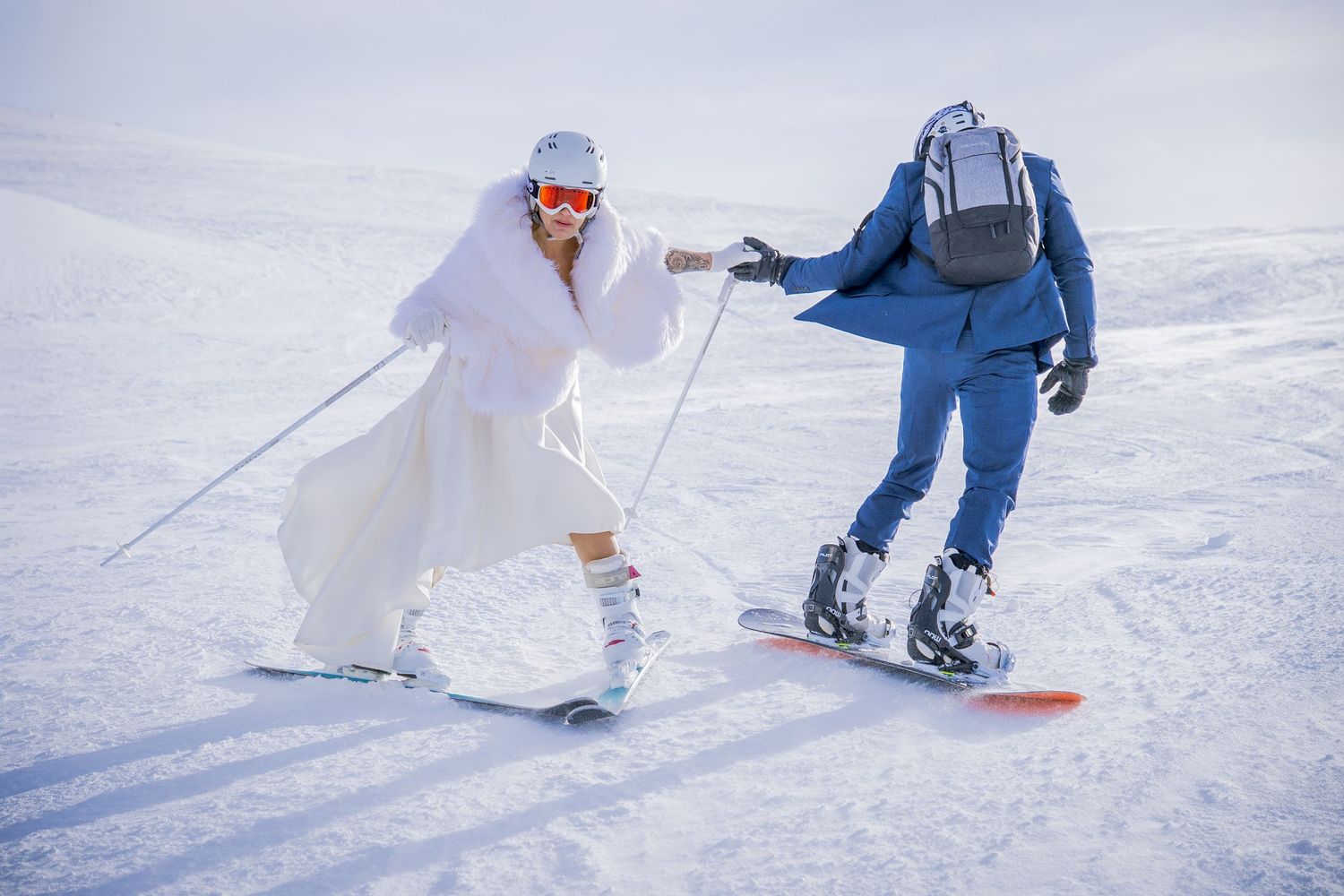 A skier in blue and white glides down a snowy slope on a bright winter day.