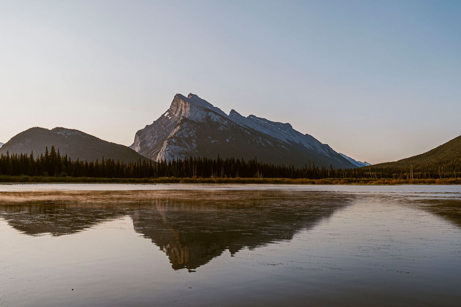 Mount Rundle reflects perfectly in the calm waters of Vermilion Lakes at sunset in Banff National Park, Canada.