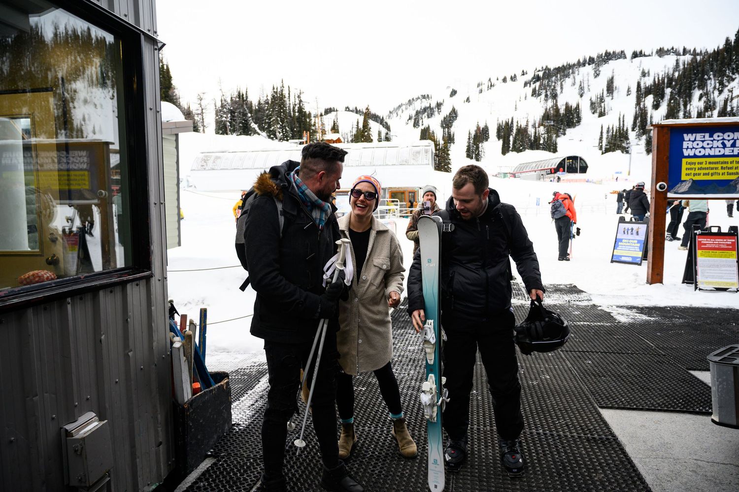 Skiers and snowboarders waiting in line at a ski lift station on a snowy mountain slope.