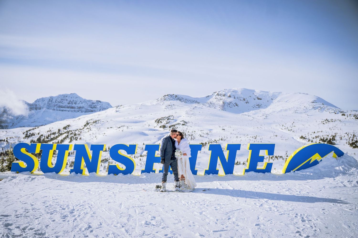 A panoramic winter landscape showing snowy mountains and blue sky with text overlaid in bright colors.