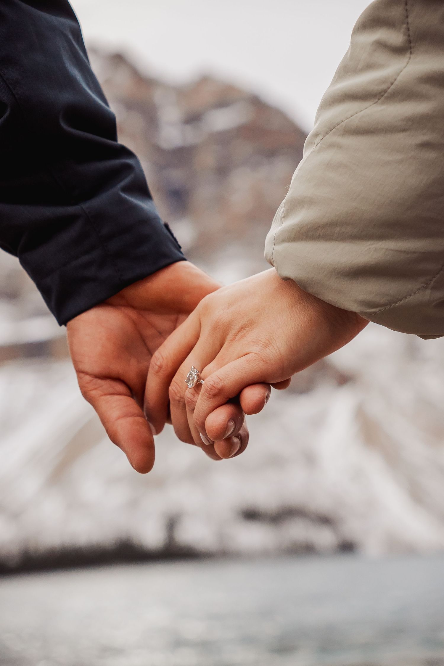 Close-up of hands joined together against a blurred mountain background.