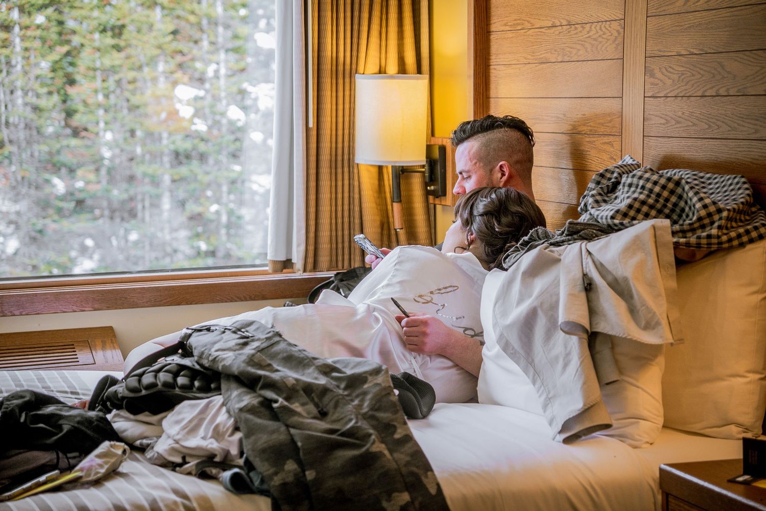A cozy cabin bedroom with wooden walls and large windows letting in natural light during different times of day.
