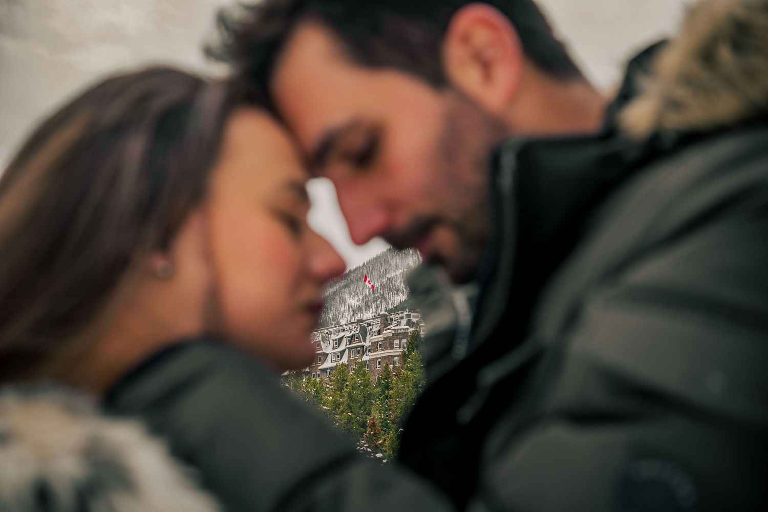 Intimate winter portrait against snowy mountain backdrop.