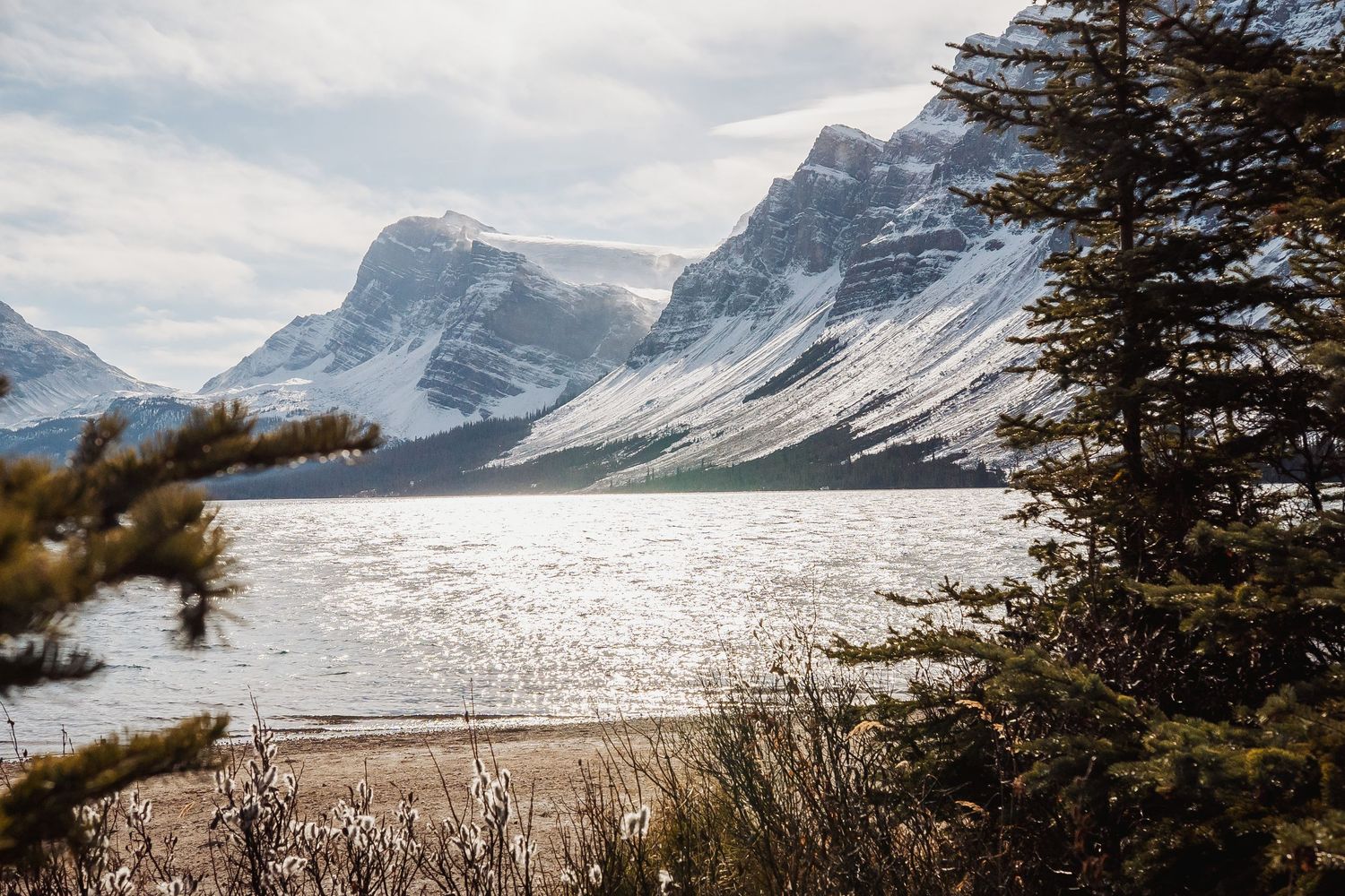 A dramatic winter landscape of snow-capped peaks and frozen lake in the Canadian Rockies.