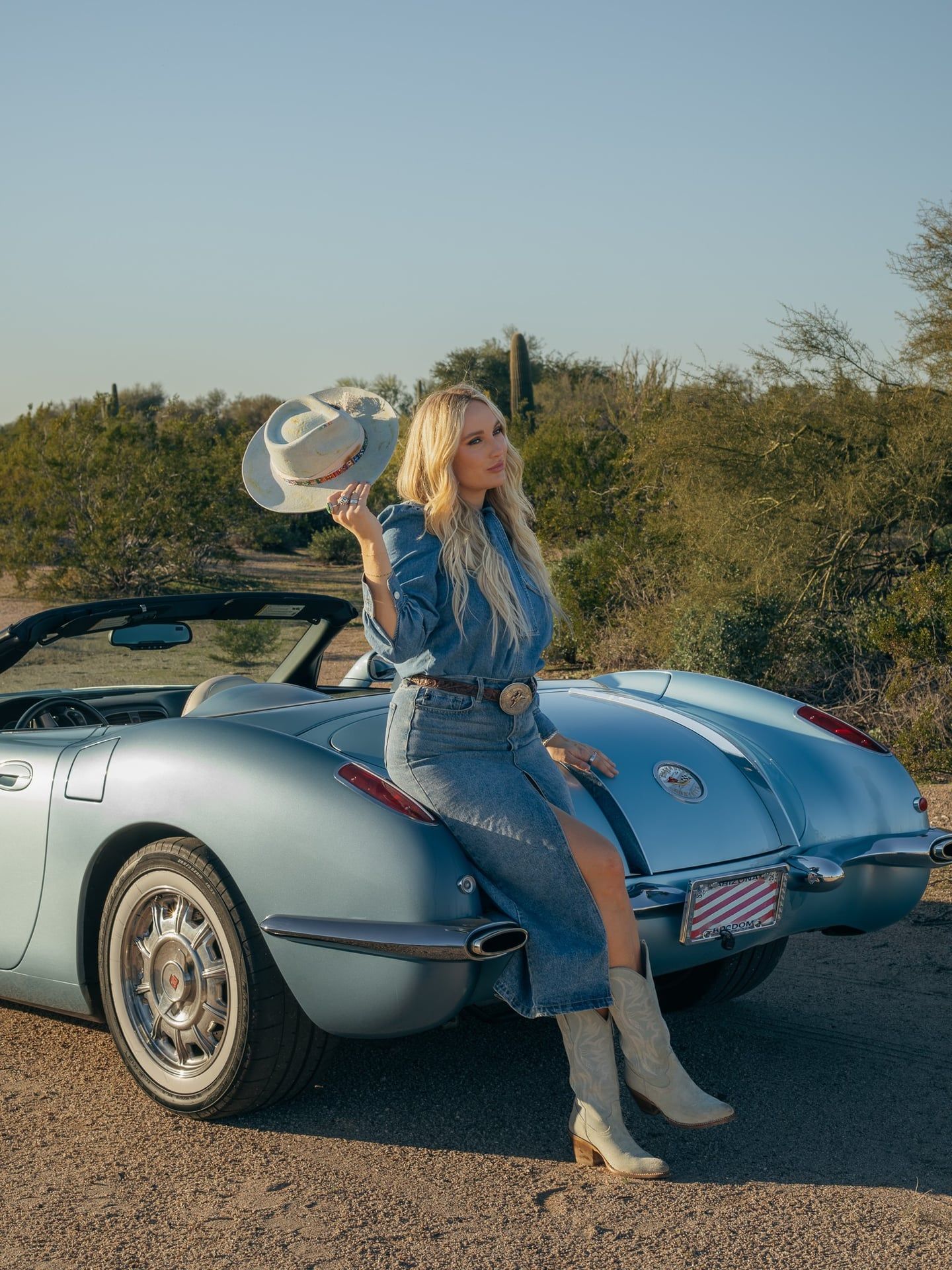 Creative fashion portrait session in Arizona desert with model posing on car during golden hour