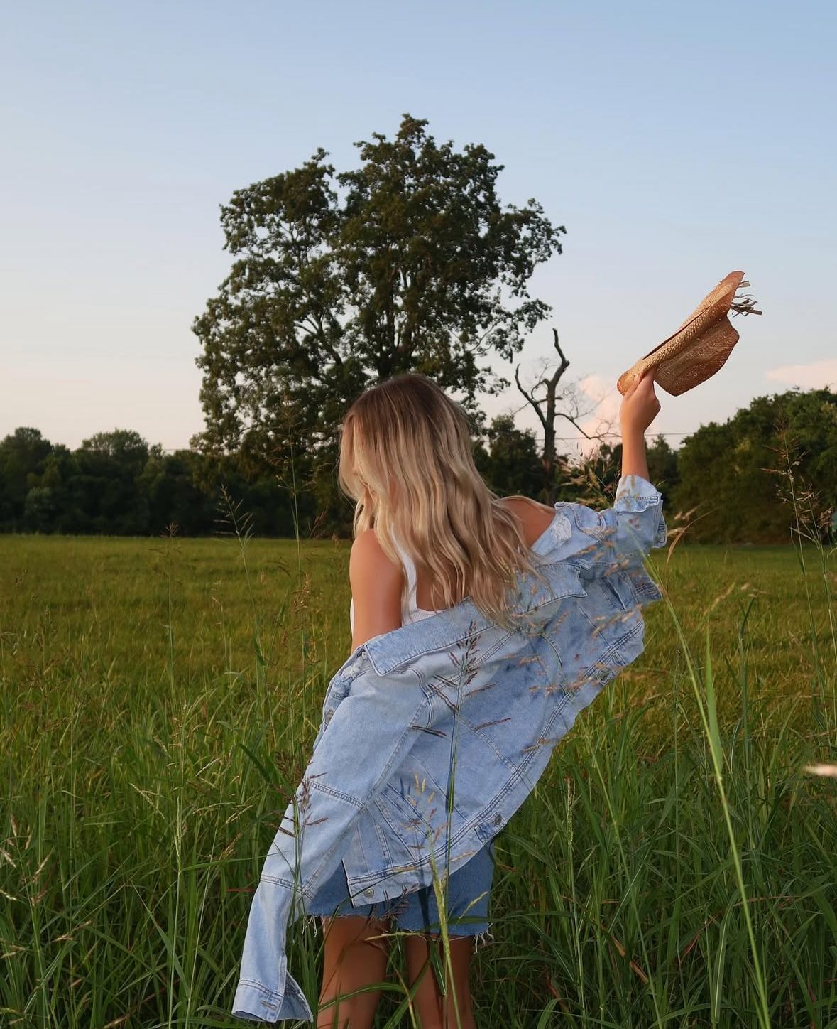 Rustic lifestyle portrait photography in Nashville Tennessee with cowgirl in open field during golden hour